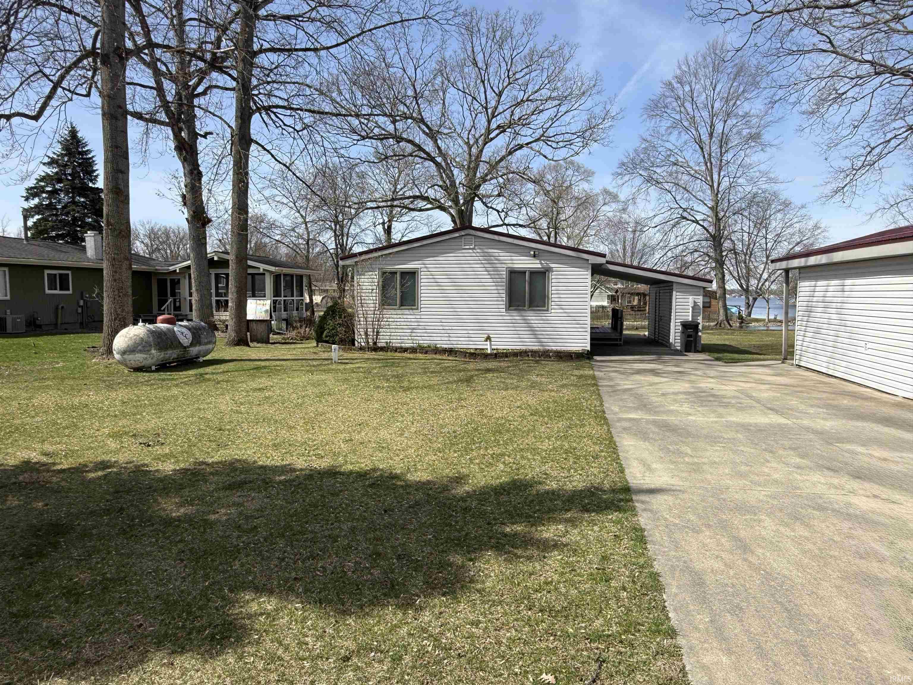 View of back of home featuring a carport, concrete driveway, and a front lawn (street side)