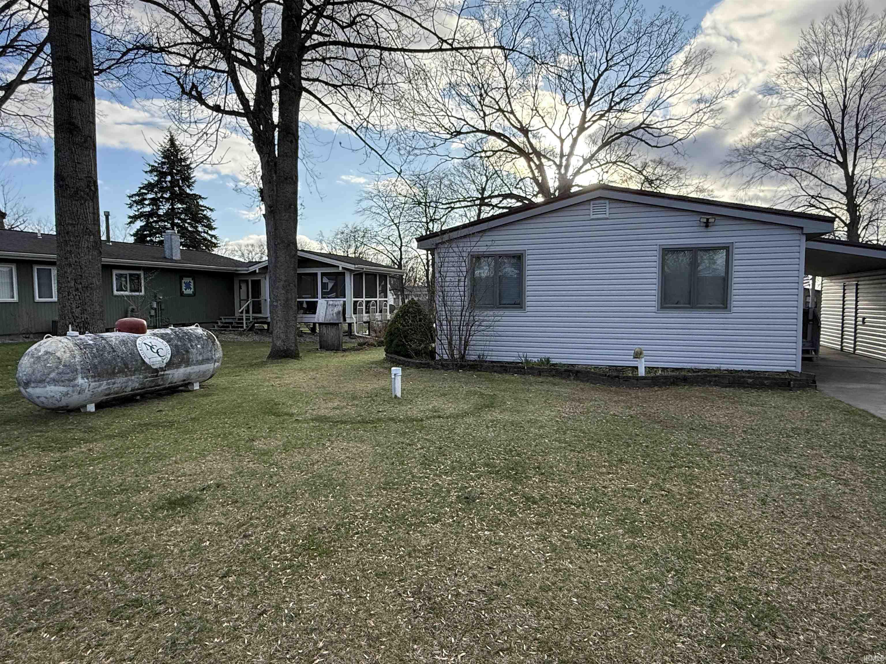 Back view of property exterior featuring an attached carport and a lawn (Street side)