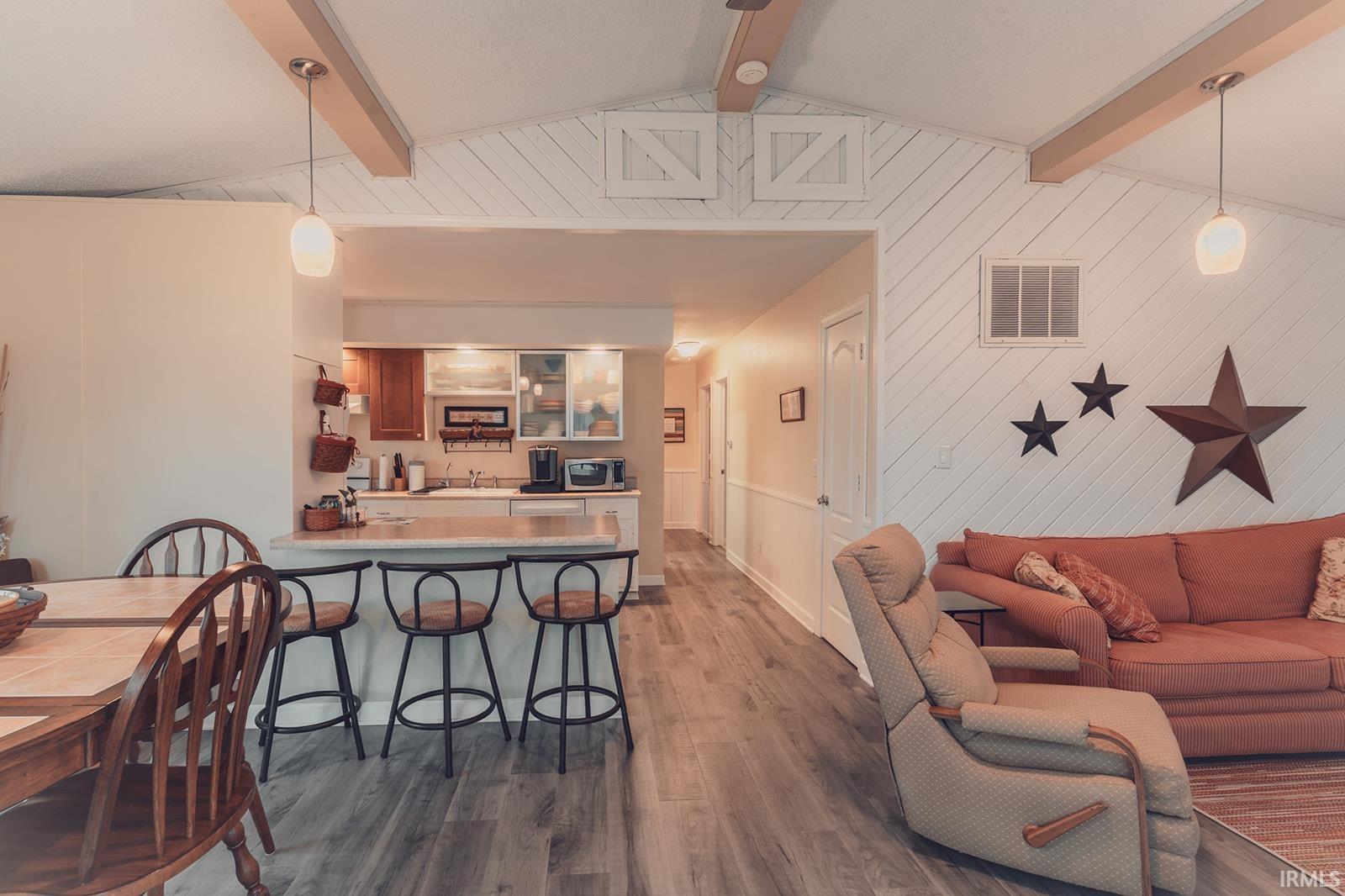 Living area with dark wood-type flooring, beam ceiling, and wood walls