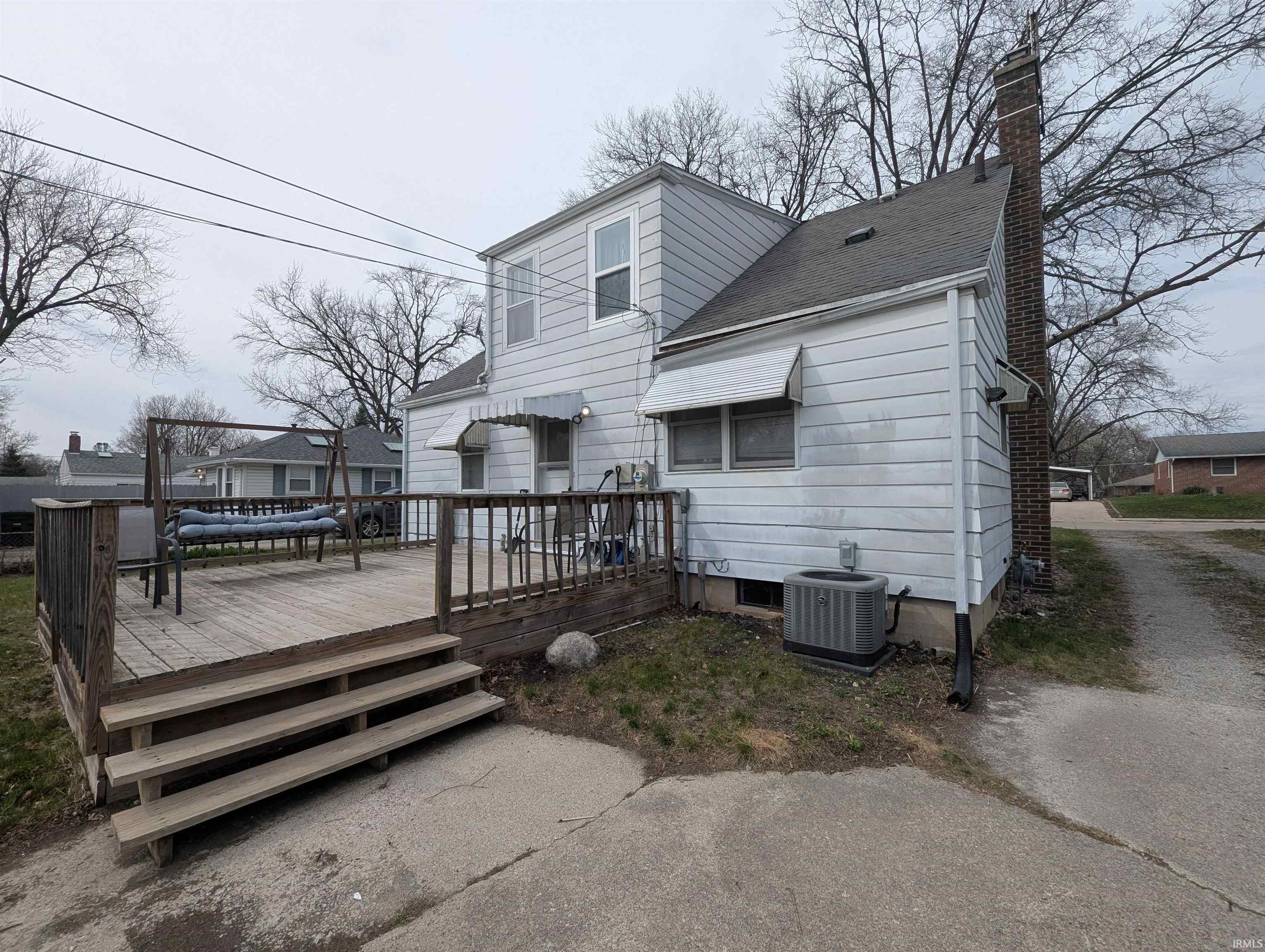 Rear view of property featuring a wooden deck, a chimney, and roof with shingles
