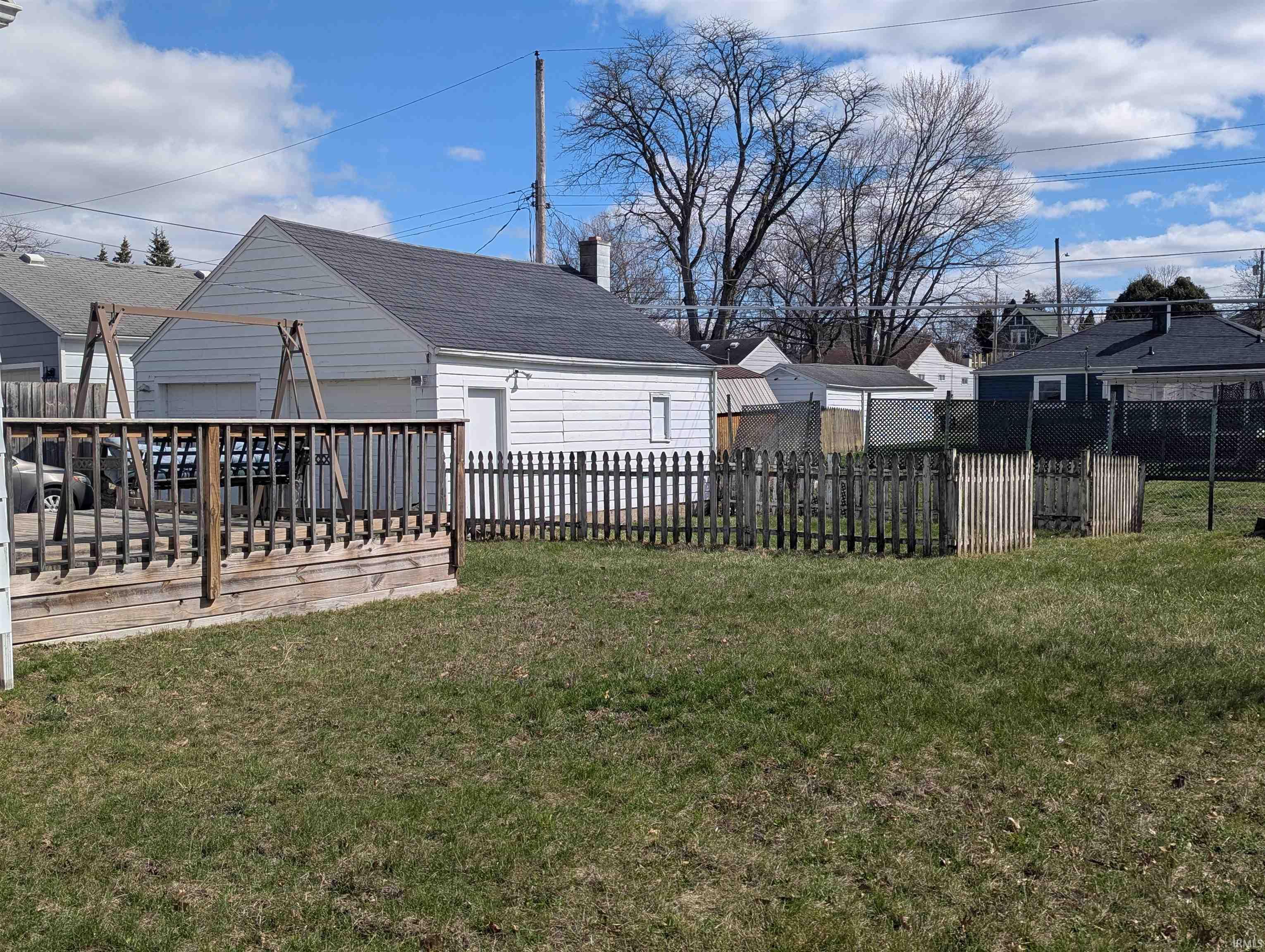 Fenced yard featuring a residential view, a deck, and a detached garage