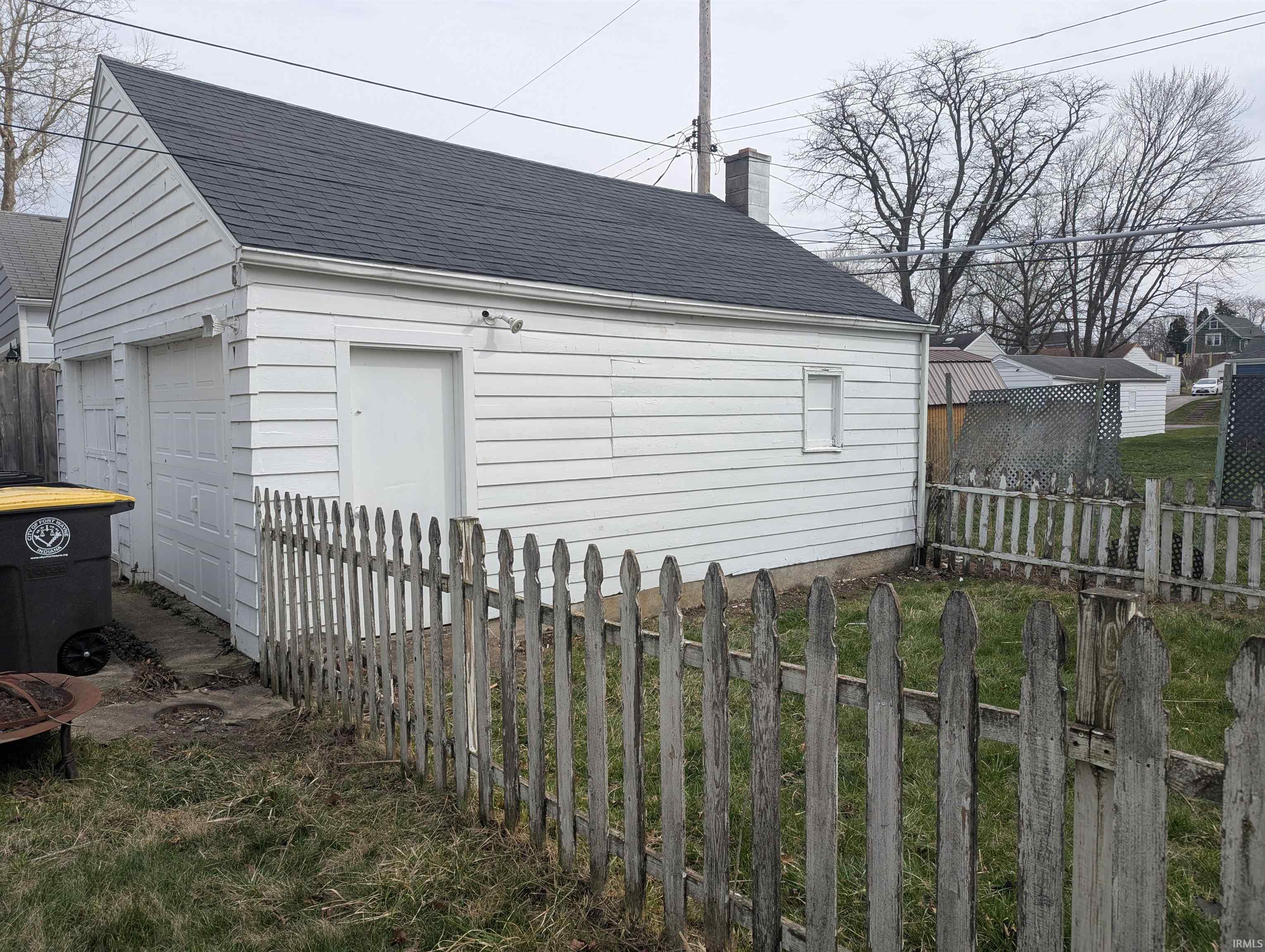 View of side of home featuring a shingled roof, a chimney, an outbuilding, and a detached garage