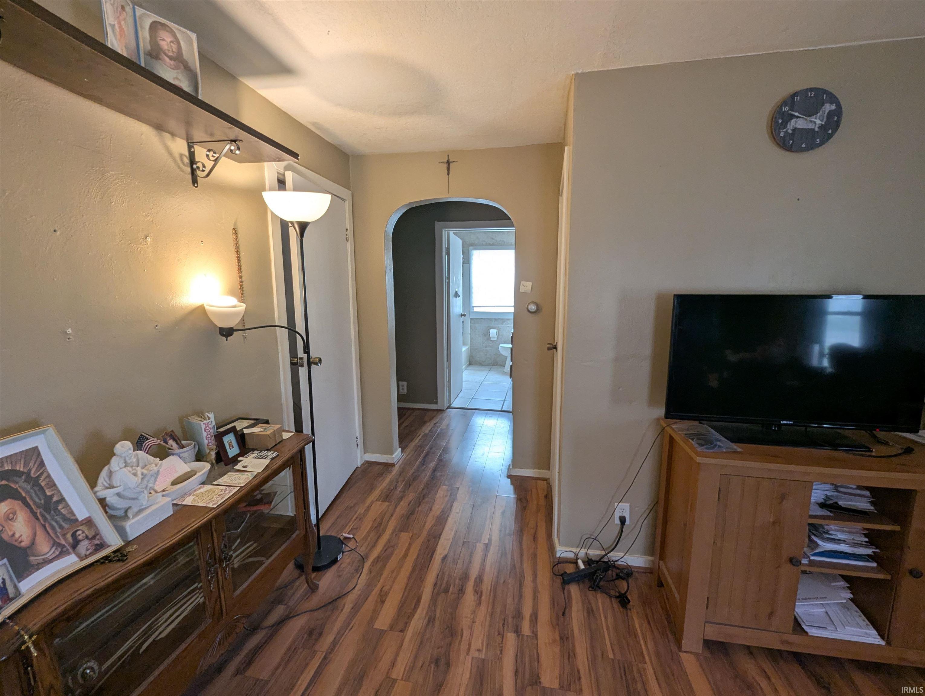 Hallway with arched walkways and dark wood finished floors