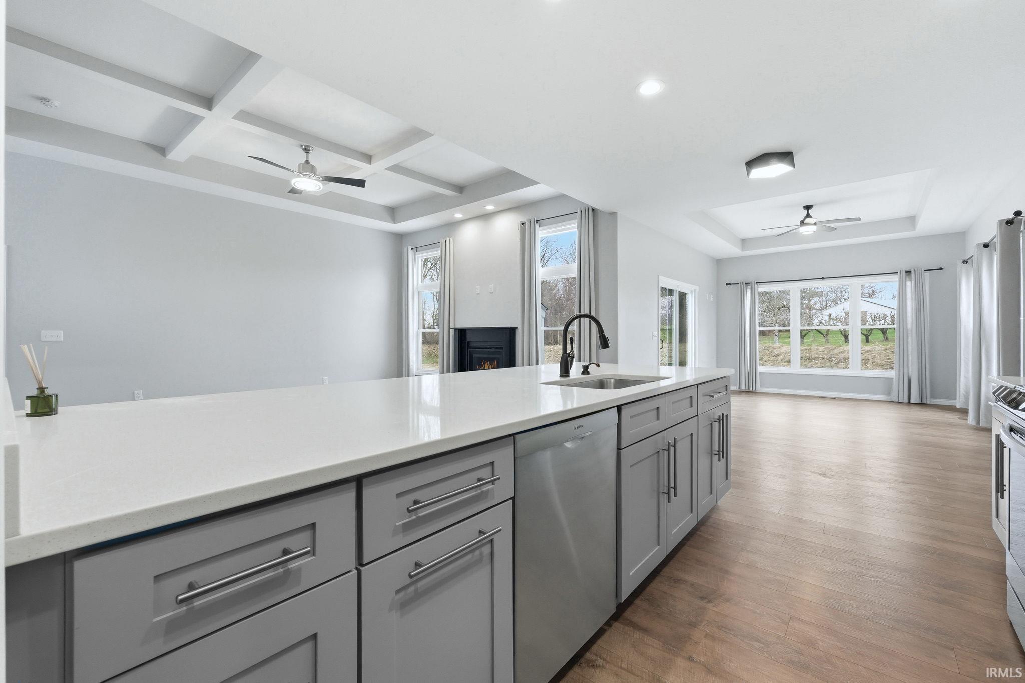 Kitchen island featuring a white countertop, gray cabinetry, and an integrated stainless steel dishwasher