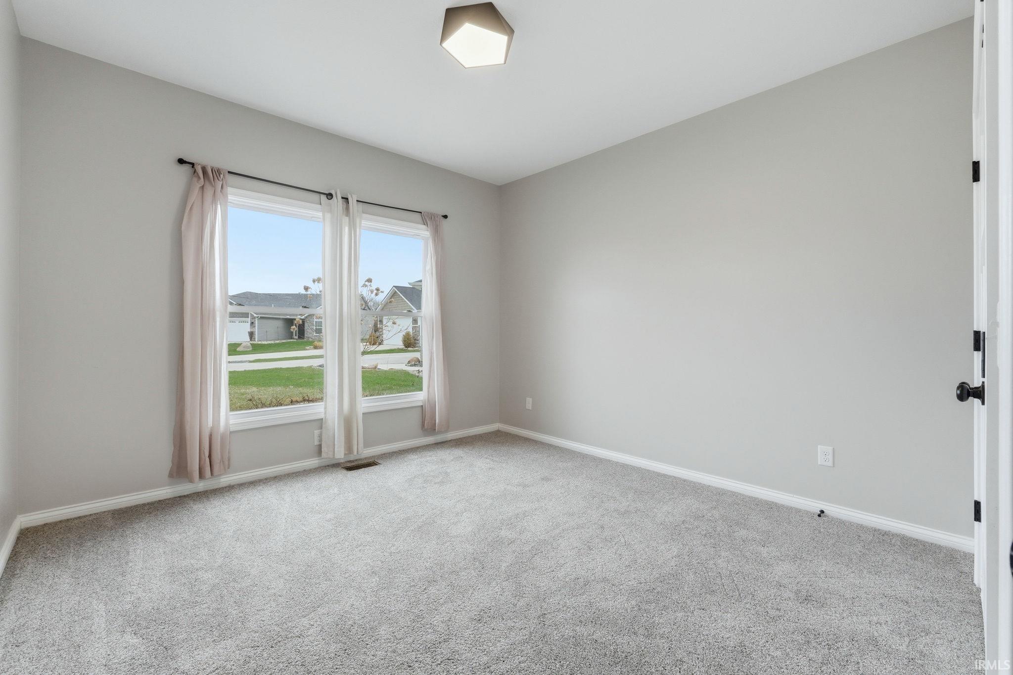 Unfurnished room featuring light carpet and baseboards
