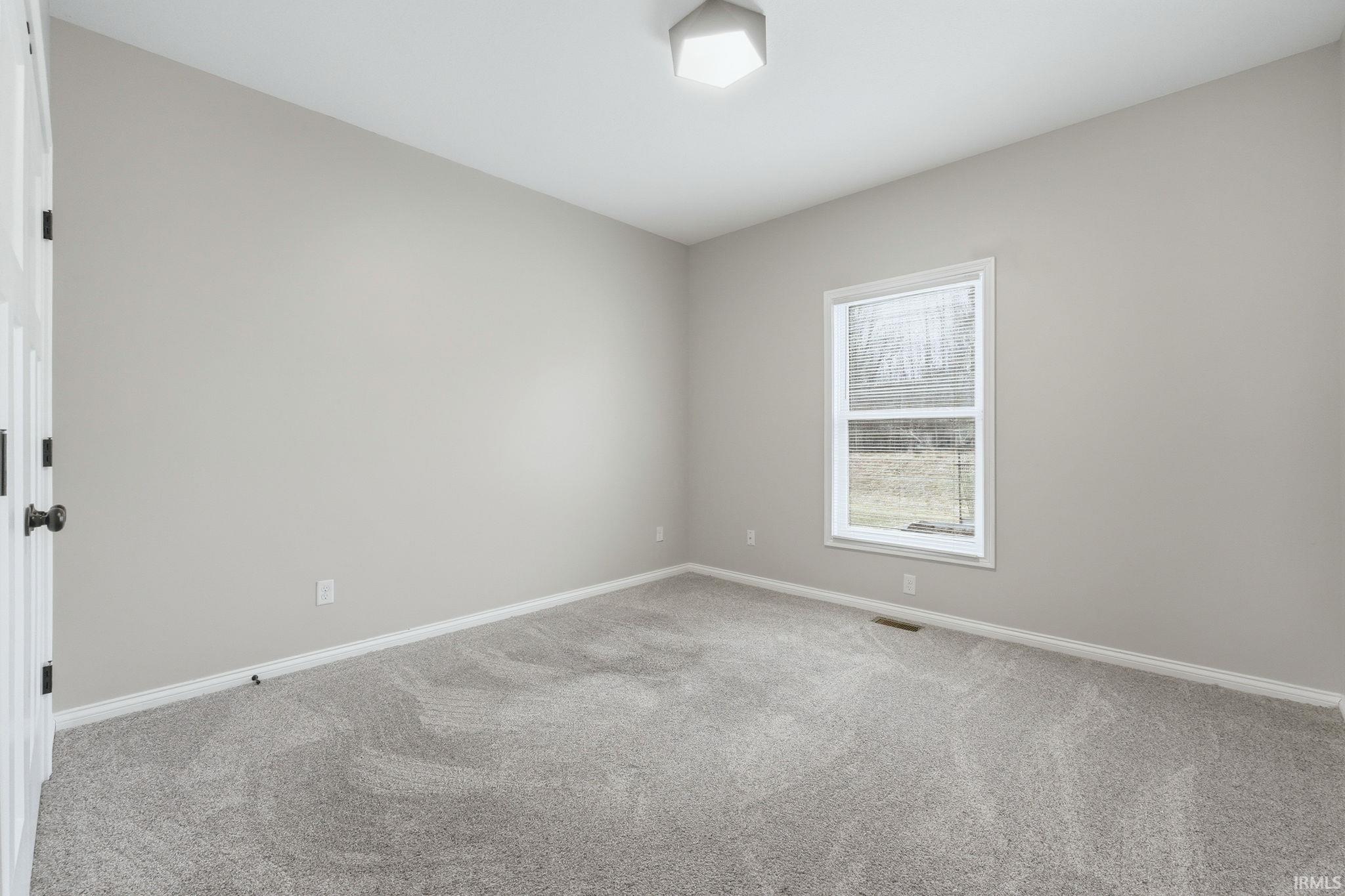 Spare room featuring light carpet and baseboards