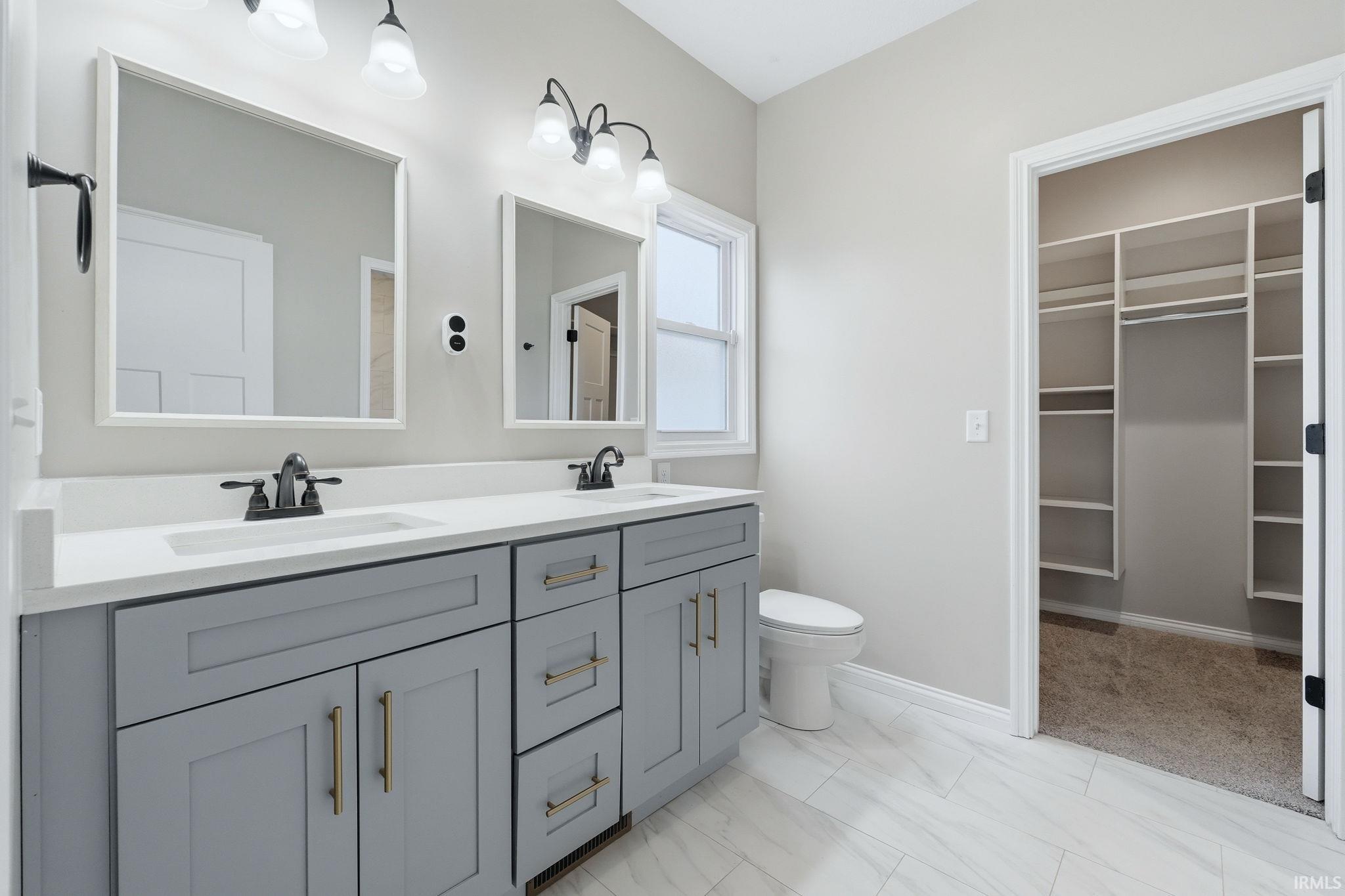 Full bathroom with double vanity and a walk in closet