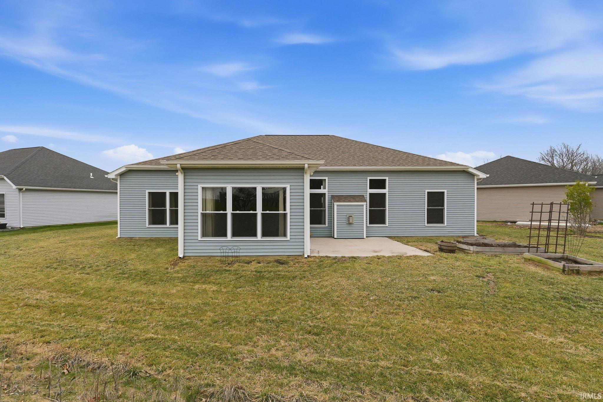 Rear view of property with a patio area, a yard, a garden, and a shingled roof