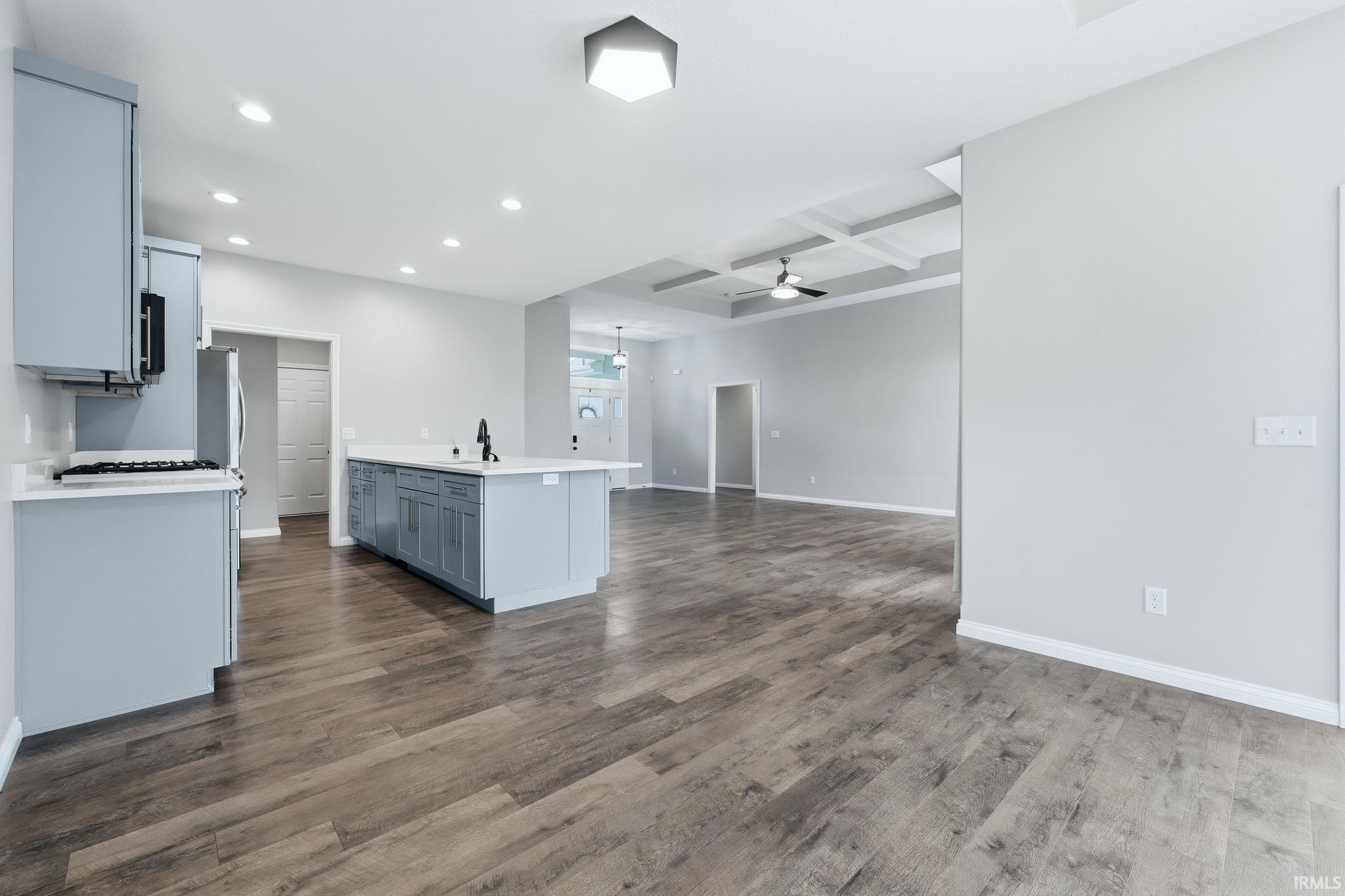 Kitchen with coffered ceiling, recessed lighting, open floor plan, gray cabinets, and dark wood-style floors