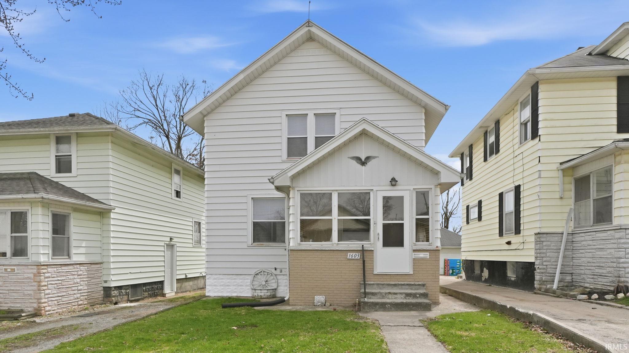 American foursquare style home with entry steps, a front yard, and board and batten siding