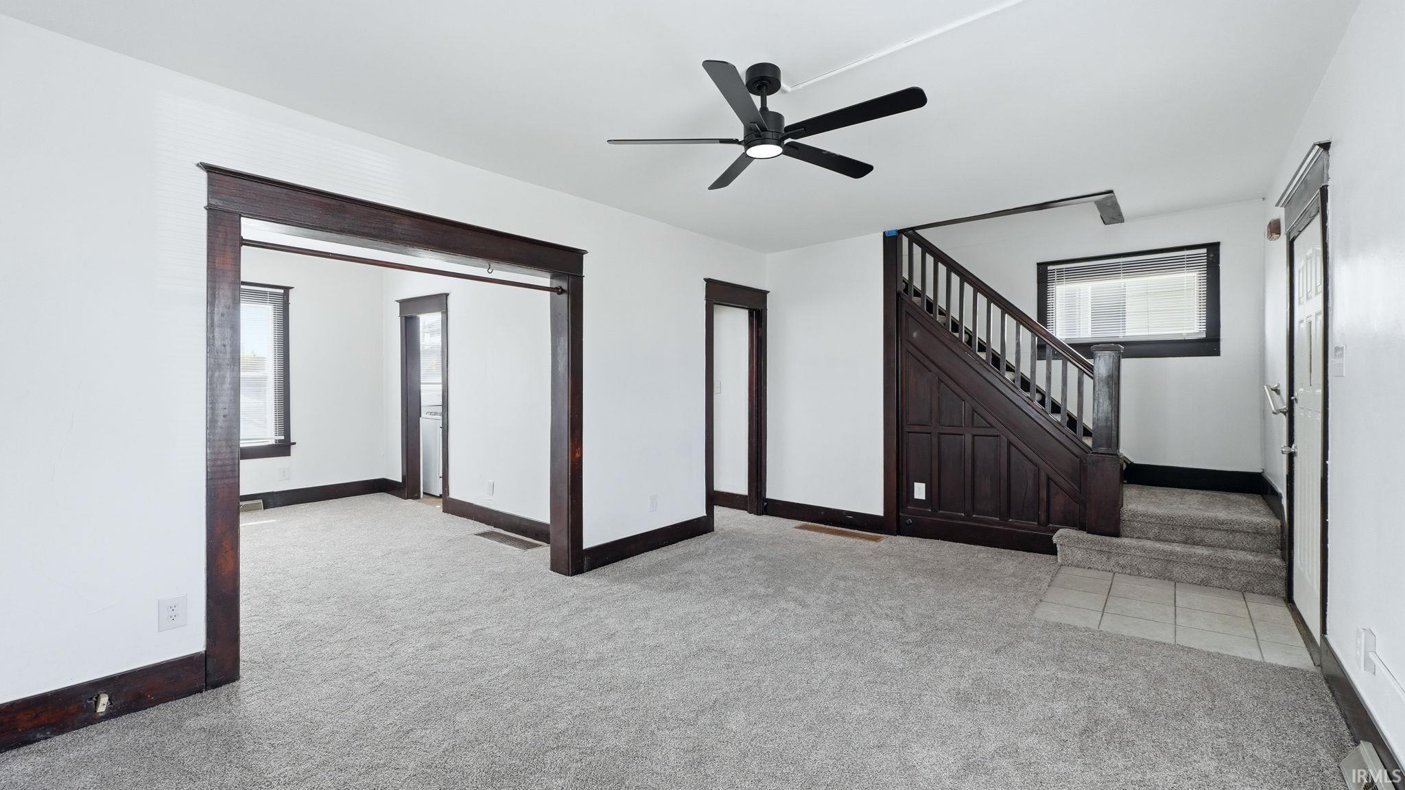 Unfurnished living room with light carpet and ceiling fan