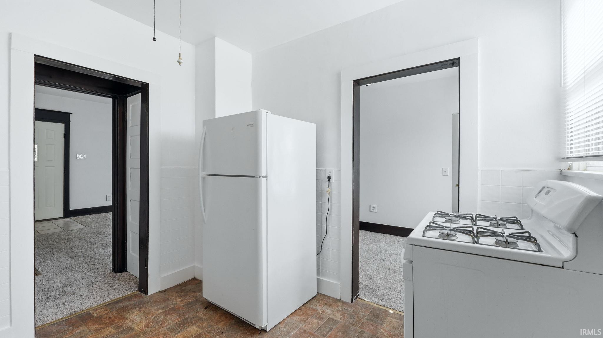 Kitchen featuring white appliances and dark carpet