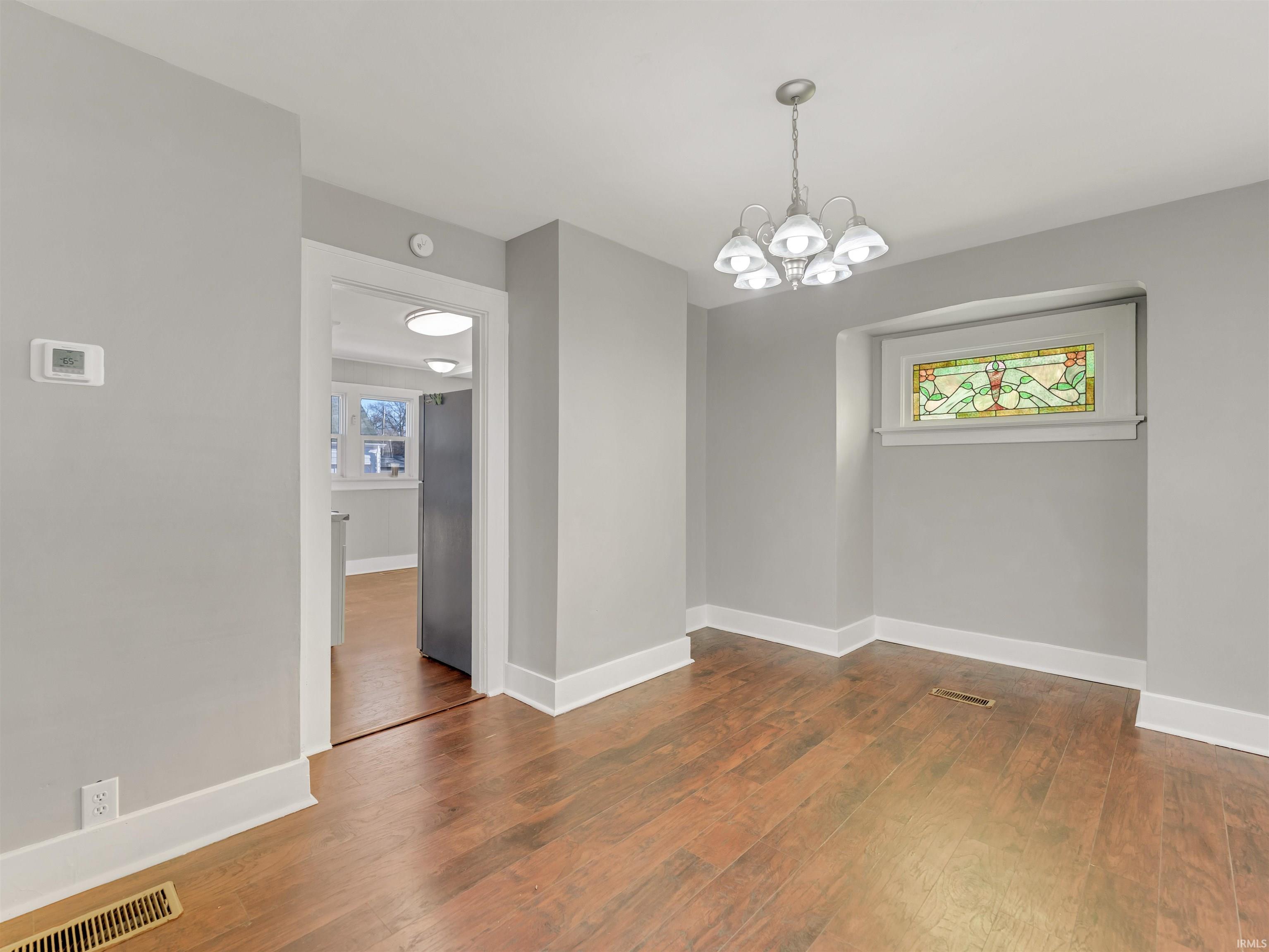 Unfurnished dining area with hanging lights and dark wood-type flooring