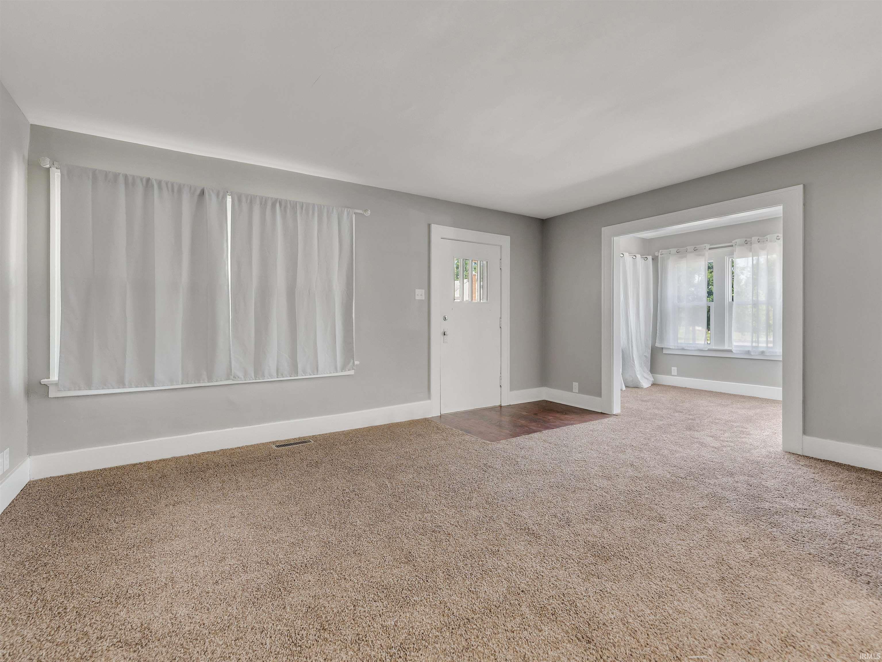 Living area featuring light gray walls, white trim, and neutral carpeting