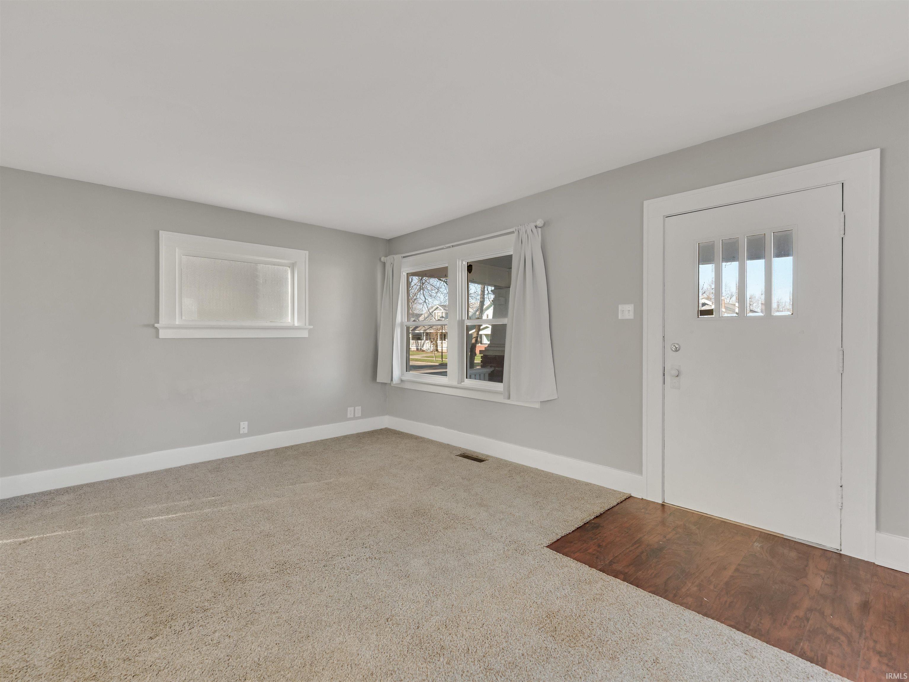 Carpeted foyer entrance with baseboards