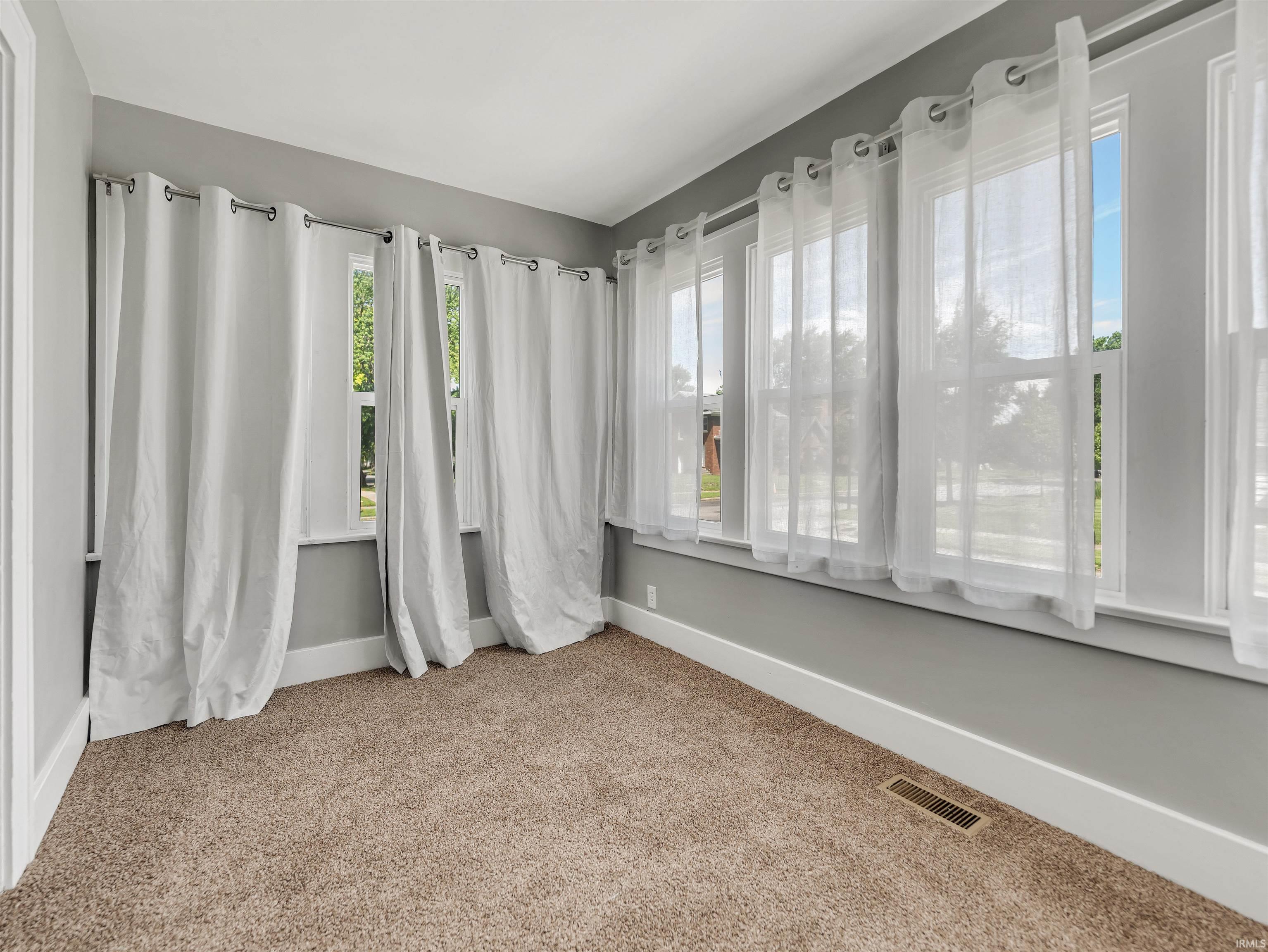 Room featuring light-colored carpet flooring, gray wall paint, and white trim