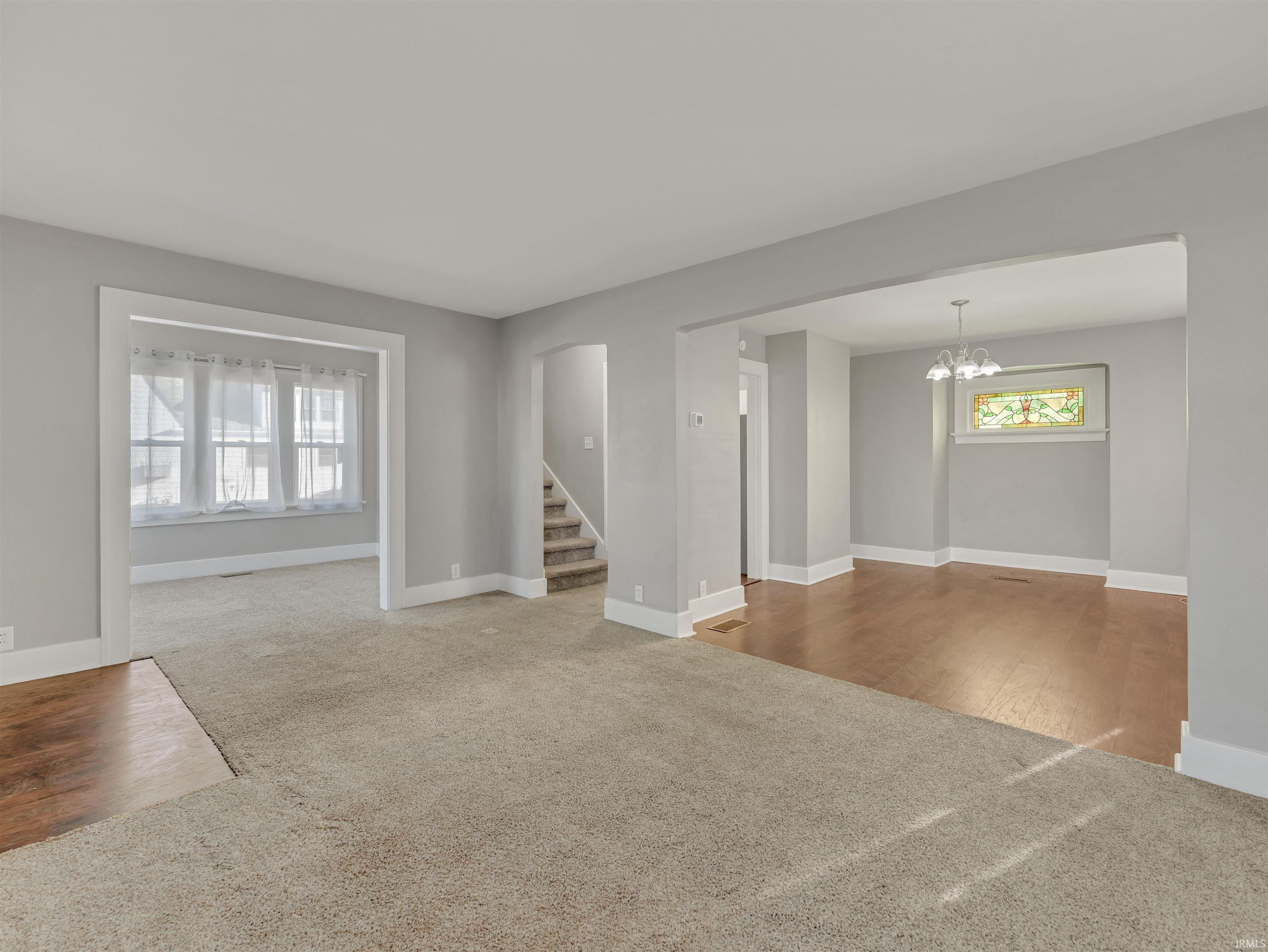 Carpeted spare room with arched walkways and hanging lights