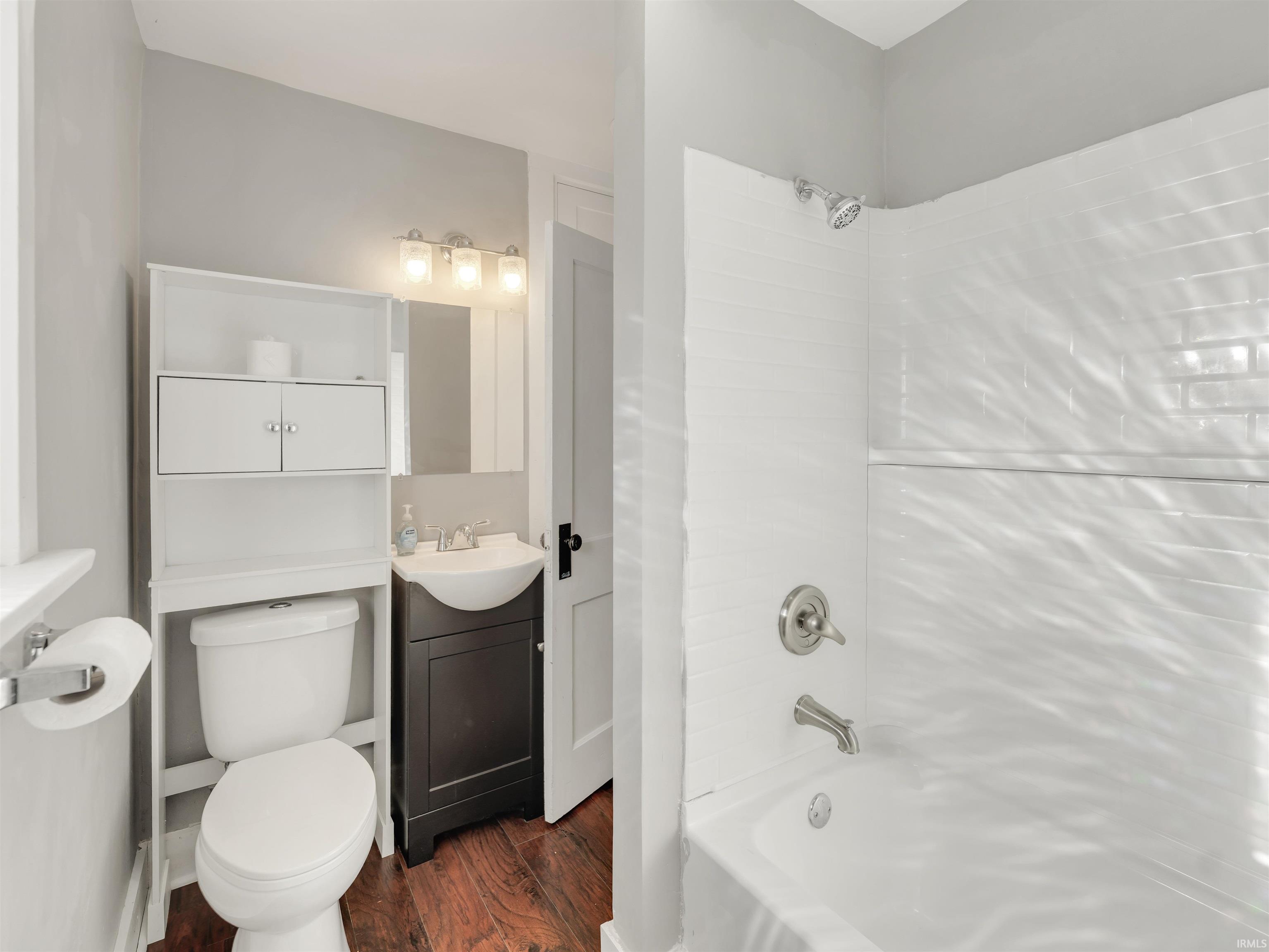 Bathroom with dark wood finished floors, vanity, and  shower combination