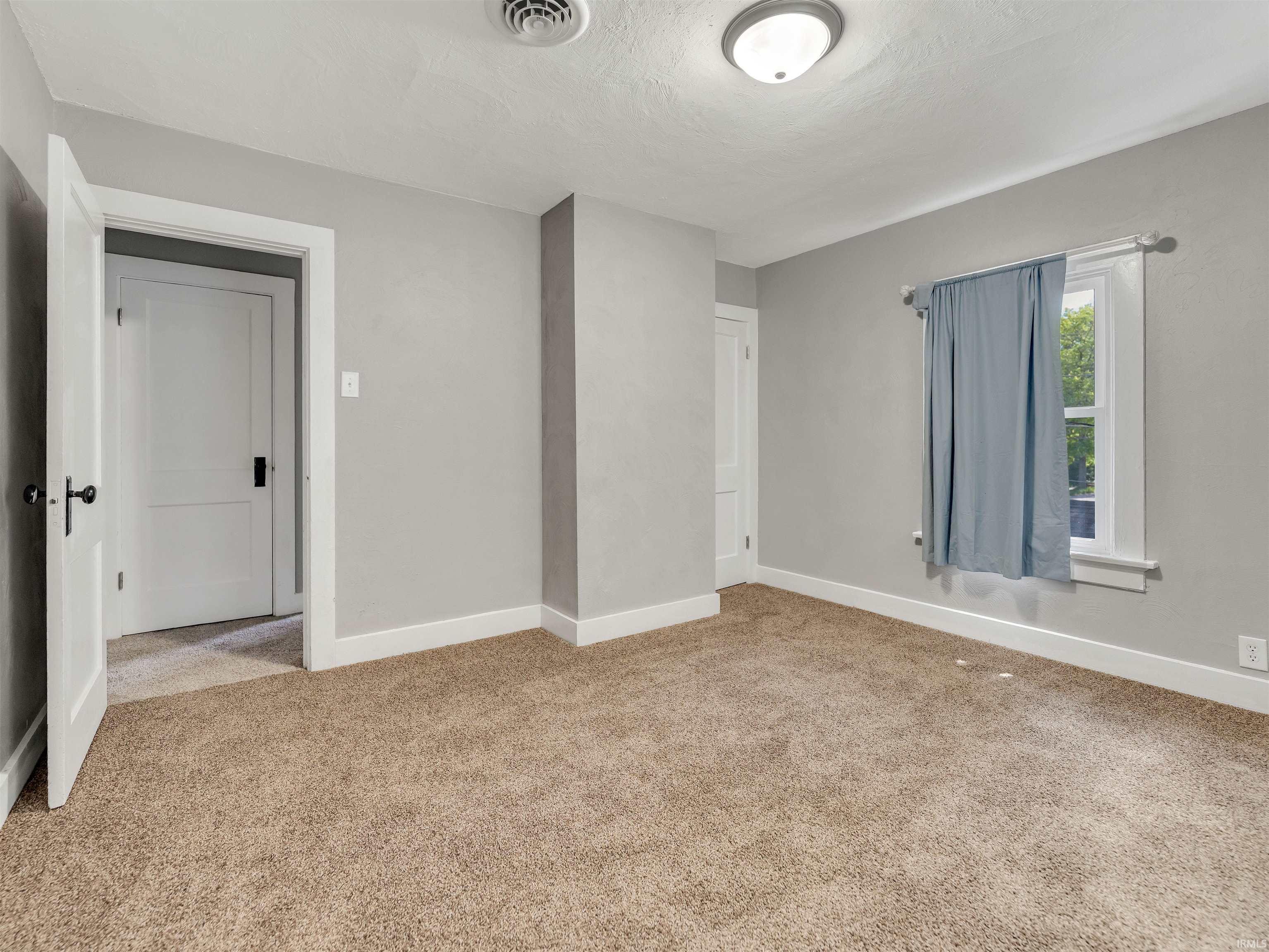 Carpeted room featuring light gray walls, white baseboards, and a white ceiling