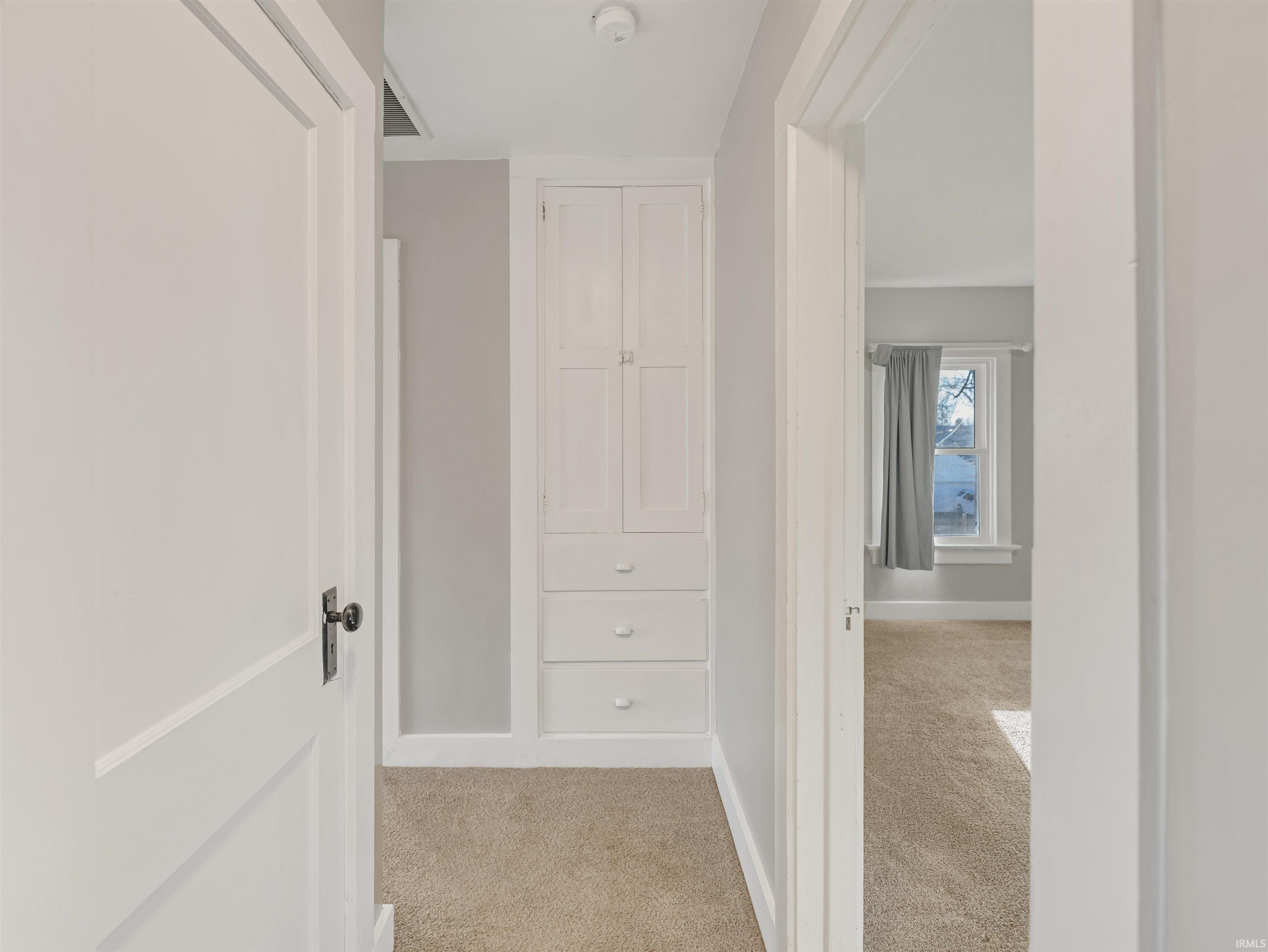 Hallway featuring light carpet