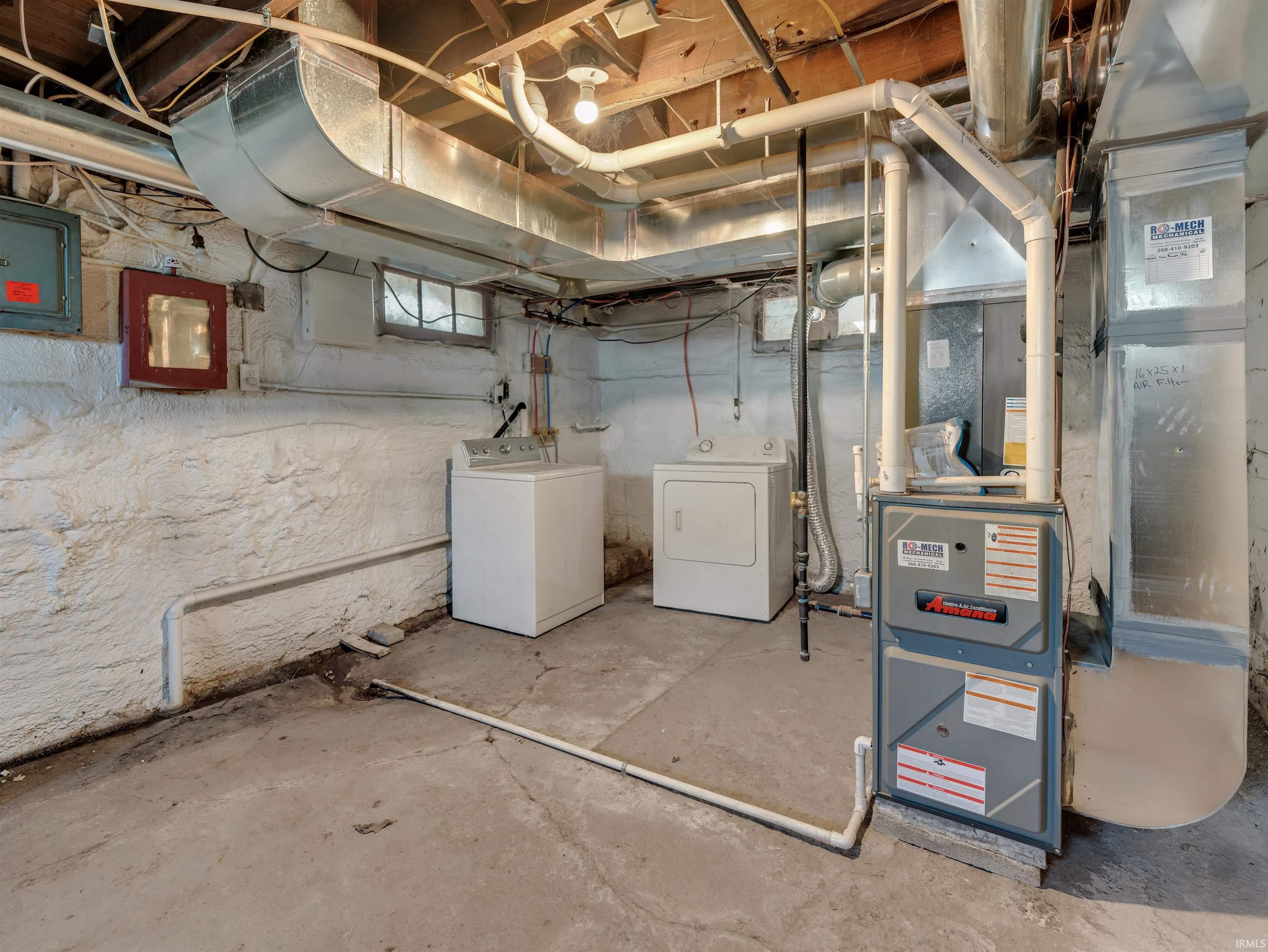 Basement featuring electric panel, heating unit, and washing machine and dryer