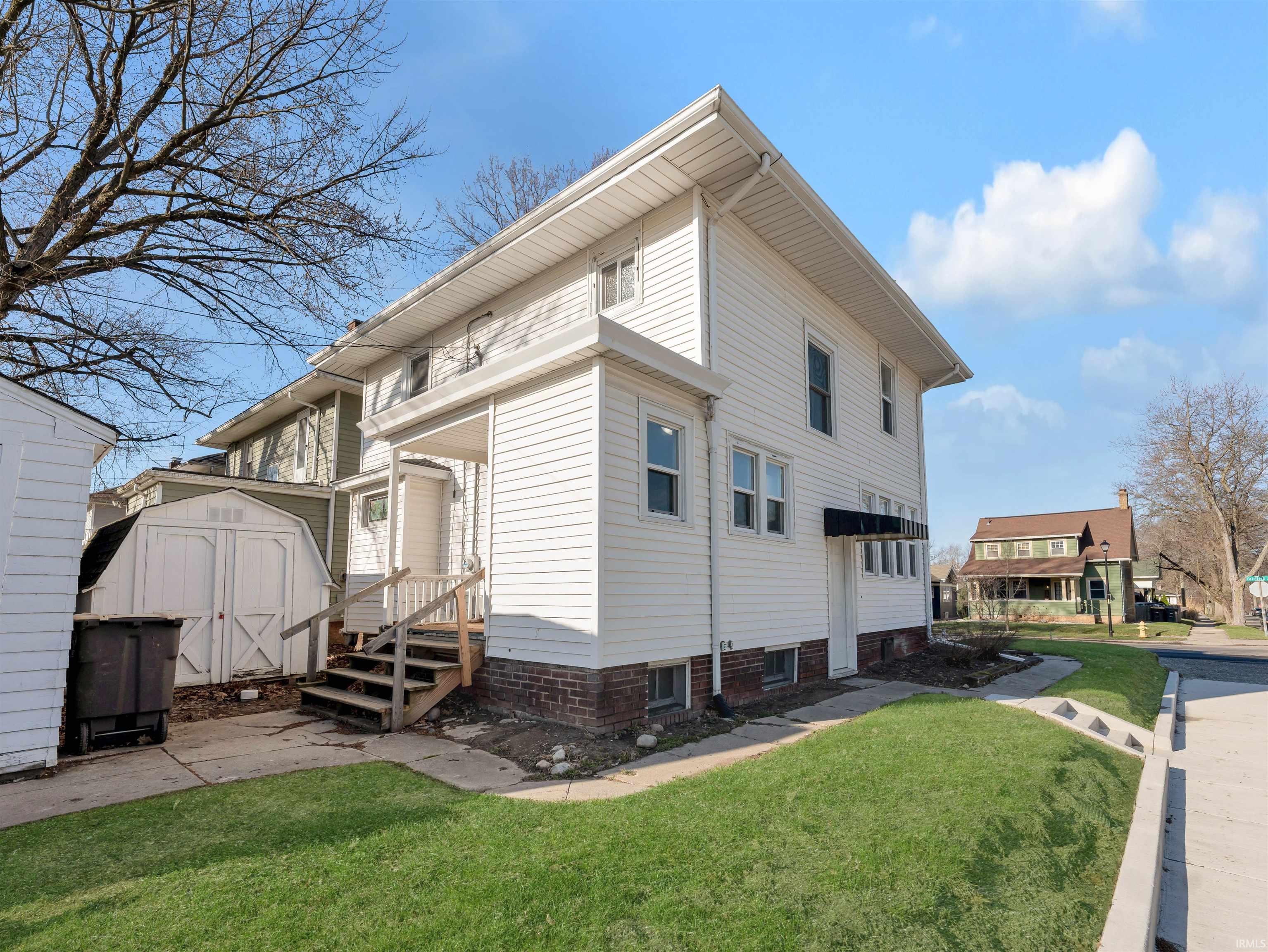 View of side of home featuring a lawn and a storage unit