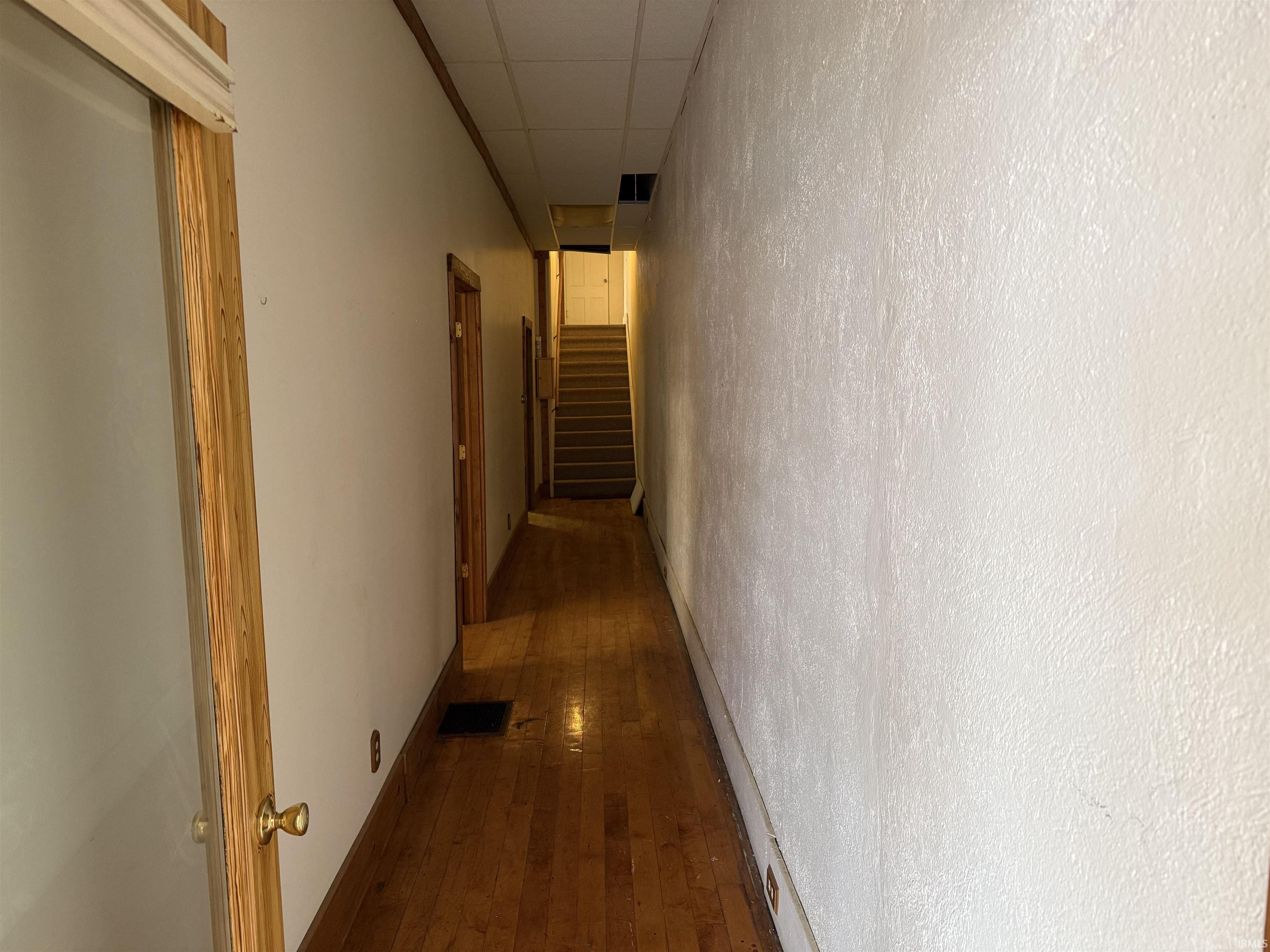Hall featuring a drop ceiling and dark wood-type flooring