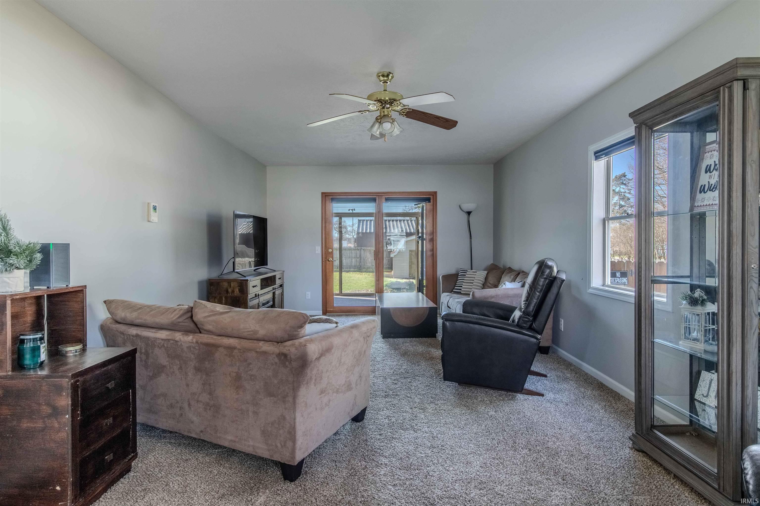 Carpeted living area featuring ceiling fan and baseboards