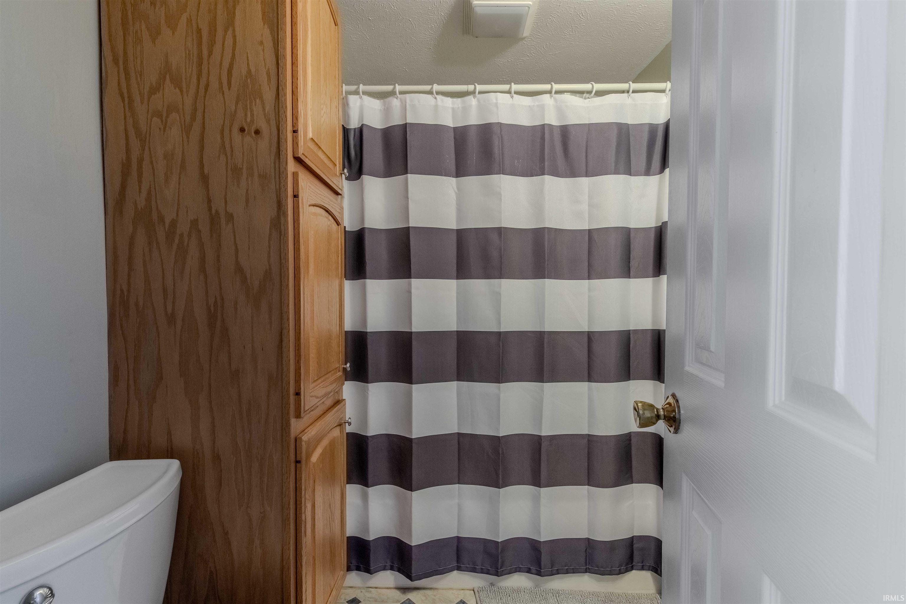 Bathroom with curtained shower and a textured ceiling