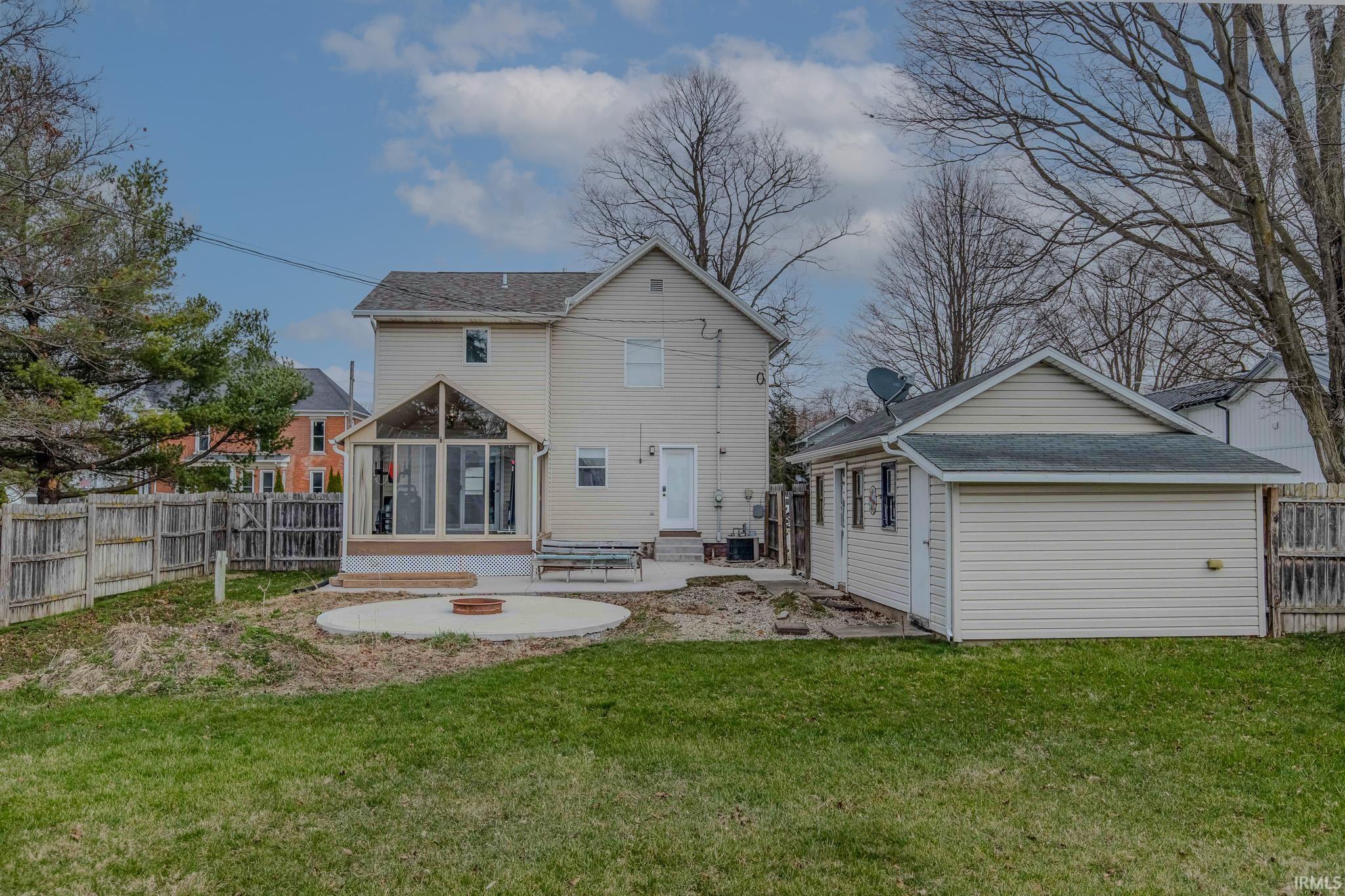 Back of property featuring a sunroom, a patio, a fenced backyard, and entry steps