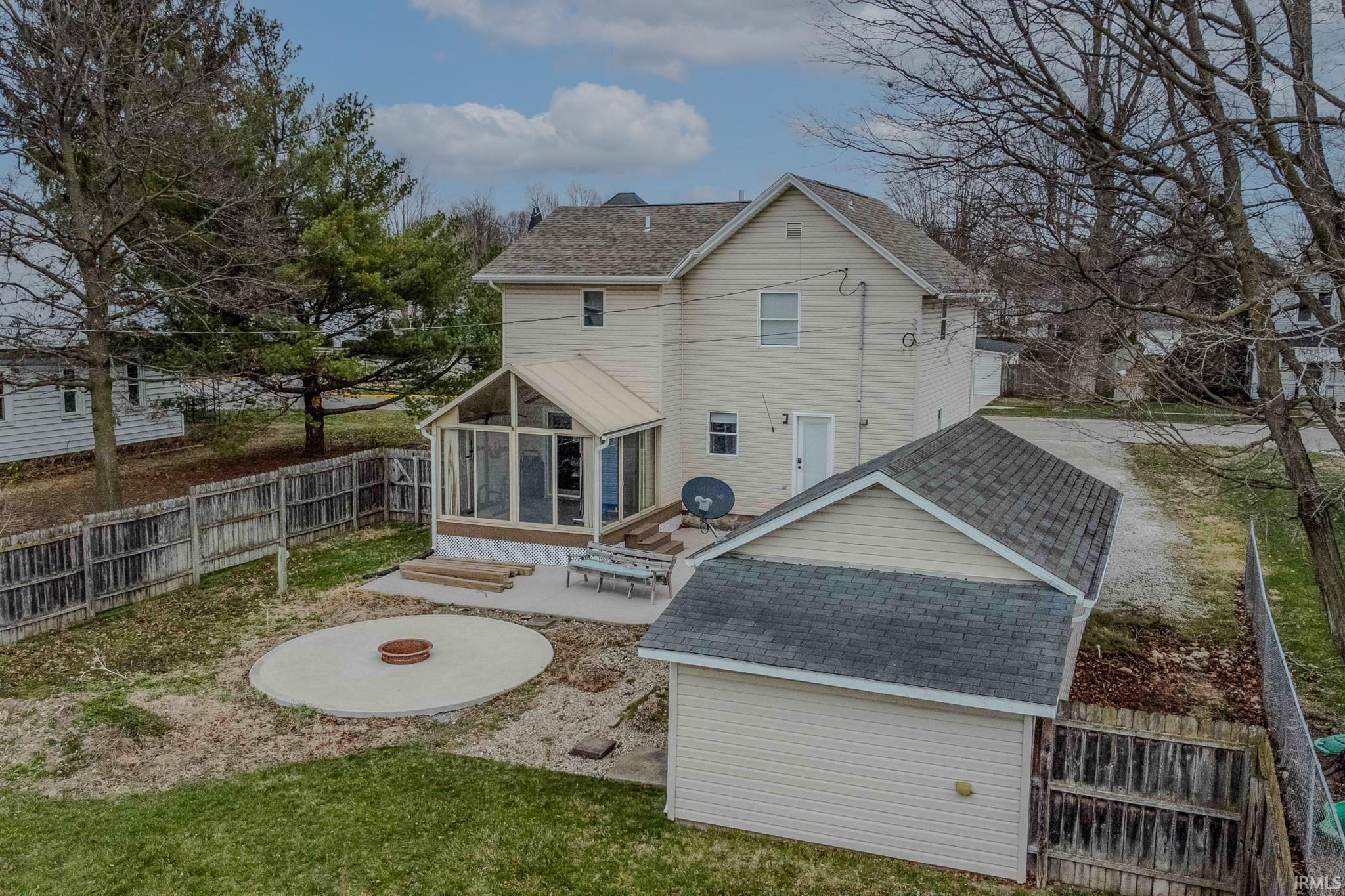 Back of house with a sunroom, a fenced backyard, a shingled roof, an outdoor fire pit, and a patio area