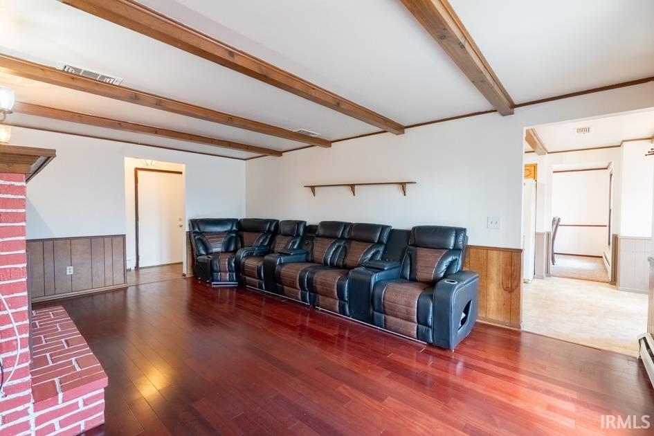 Living area with wainscoting, wooden walls, beamed ceiling, and hardwood / wood-style floors