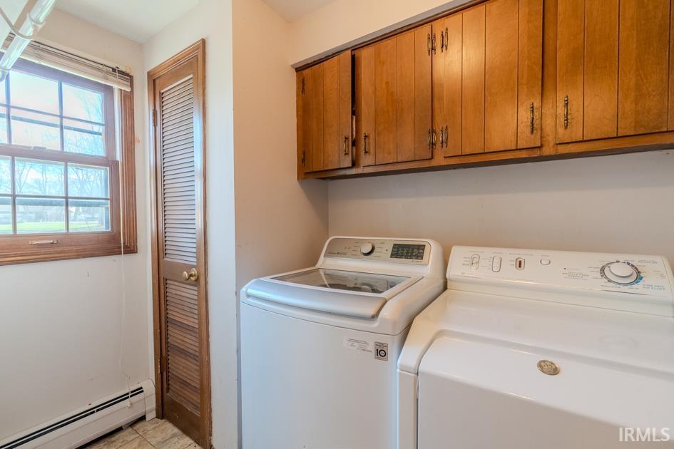 Laundry area featuring a baseboard radiator, independent washer and dryer, and cabinet space