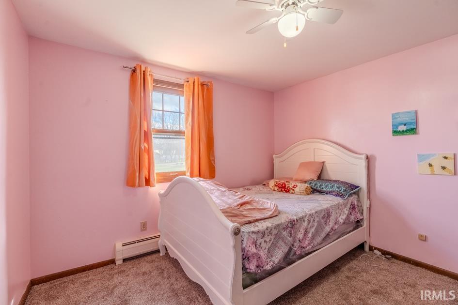 Bedroom with baseboard heating, a ceiling fan, and light carpet
