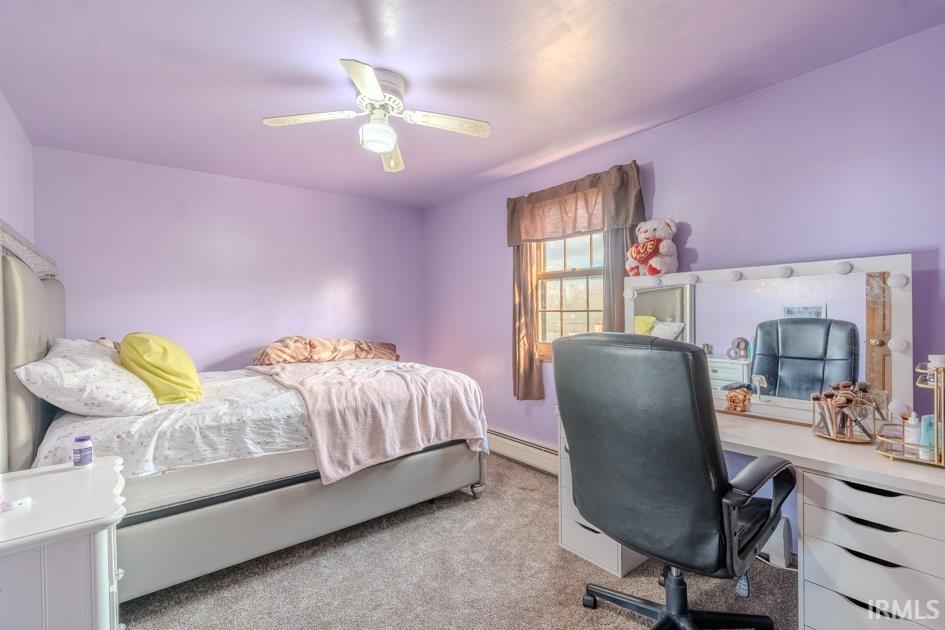 Bedroom featuring a desk, carpet, a baseboard radiator, and ceiling fan