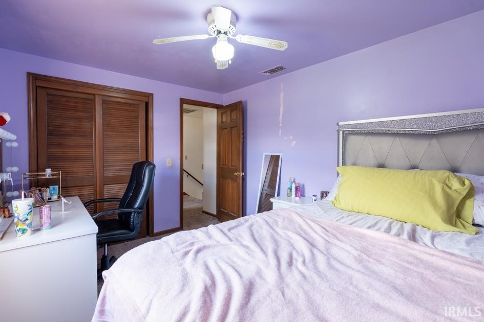 Bedroom featuring an office area, a closet, a ceiling fan, and dark colored carpet