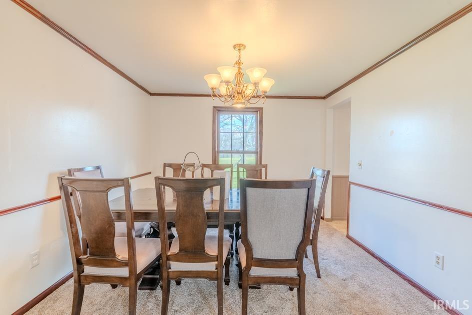 Dining room featuring light carpet, ornamental molding, and hanging lights