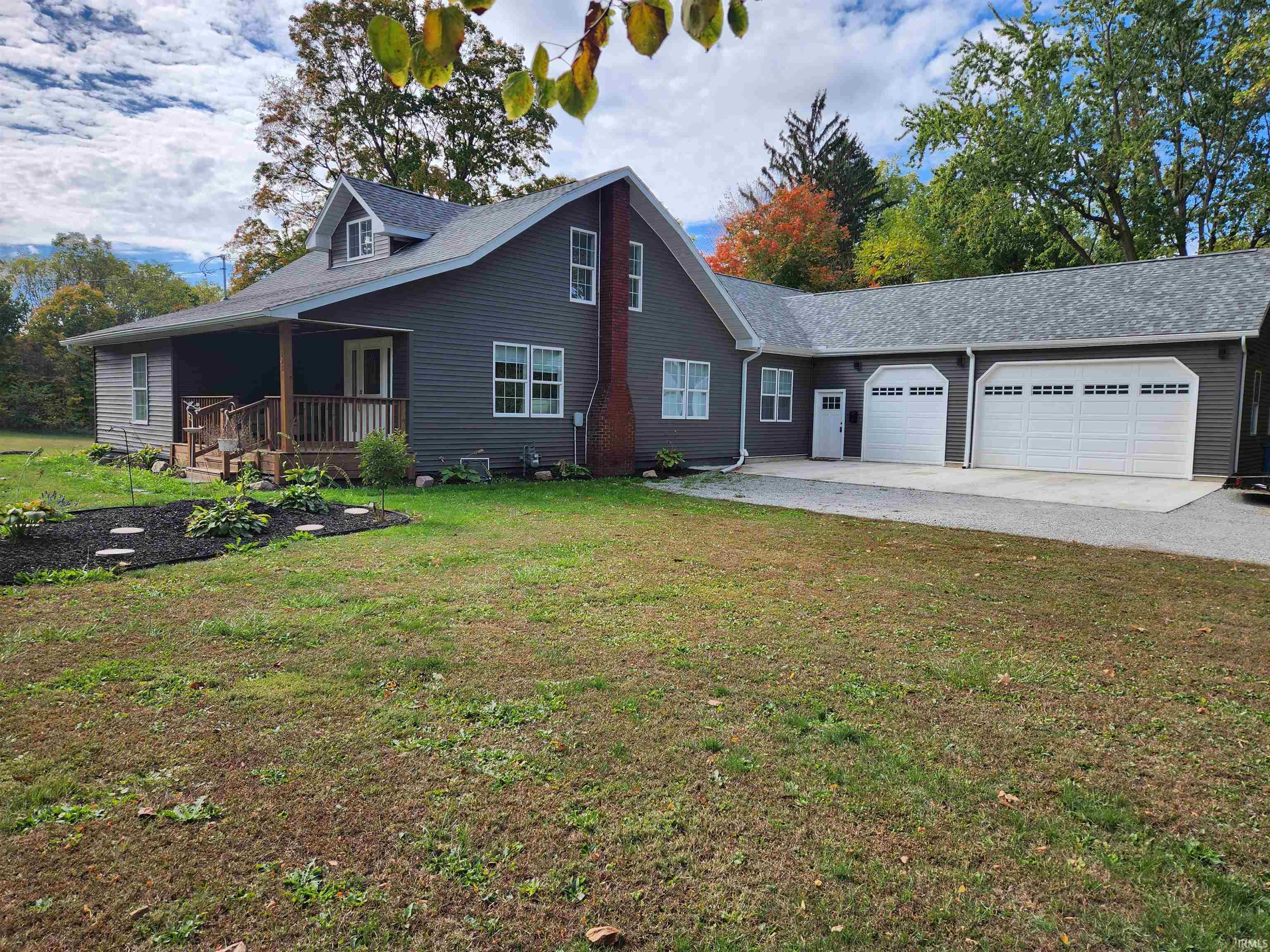 View of front of home with a garage, a front lawn, a porch, and driveway