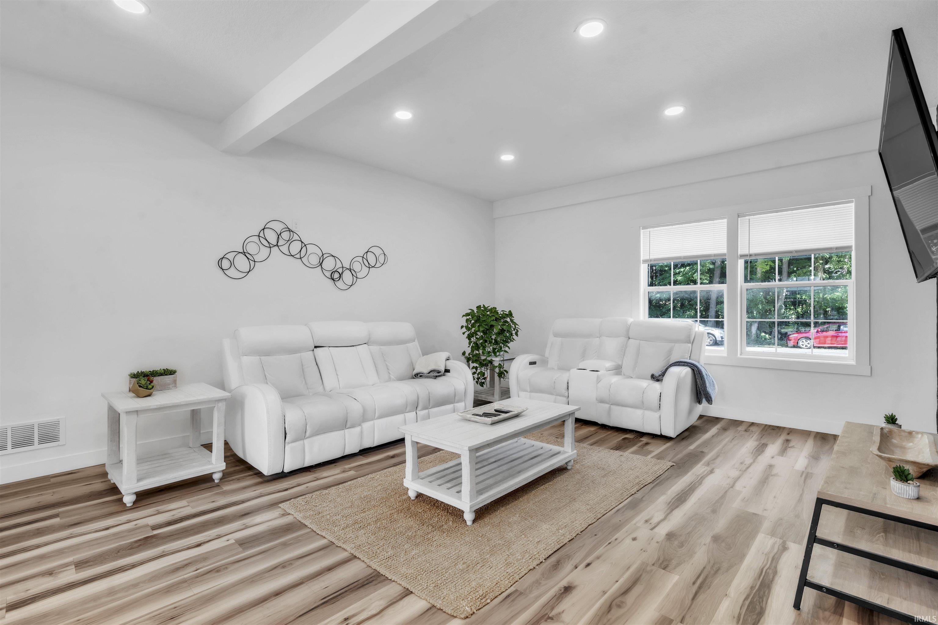 Living room featuring recessed lighting, beam ceiling, and light wood-style floors