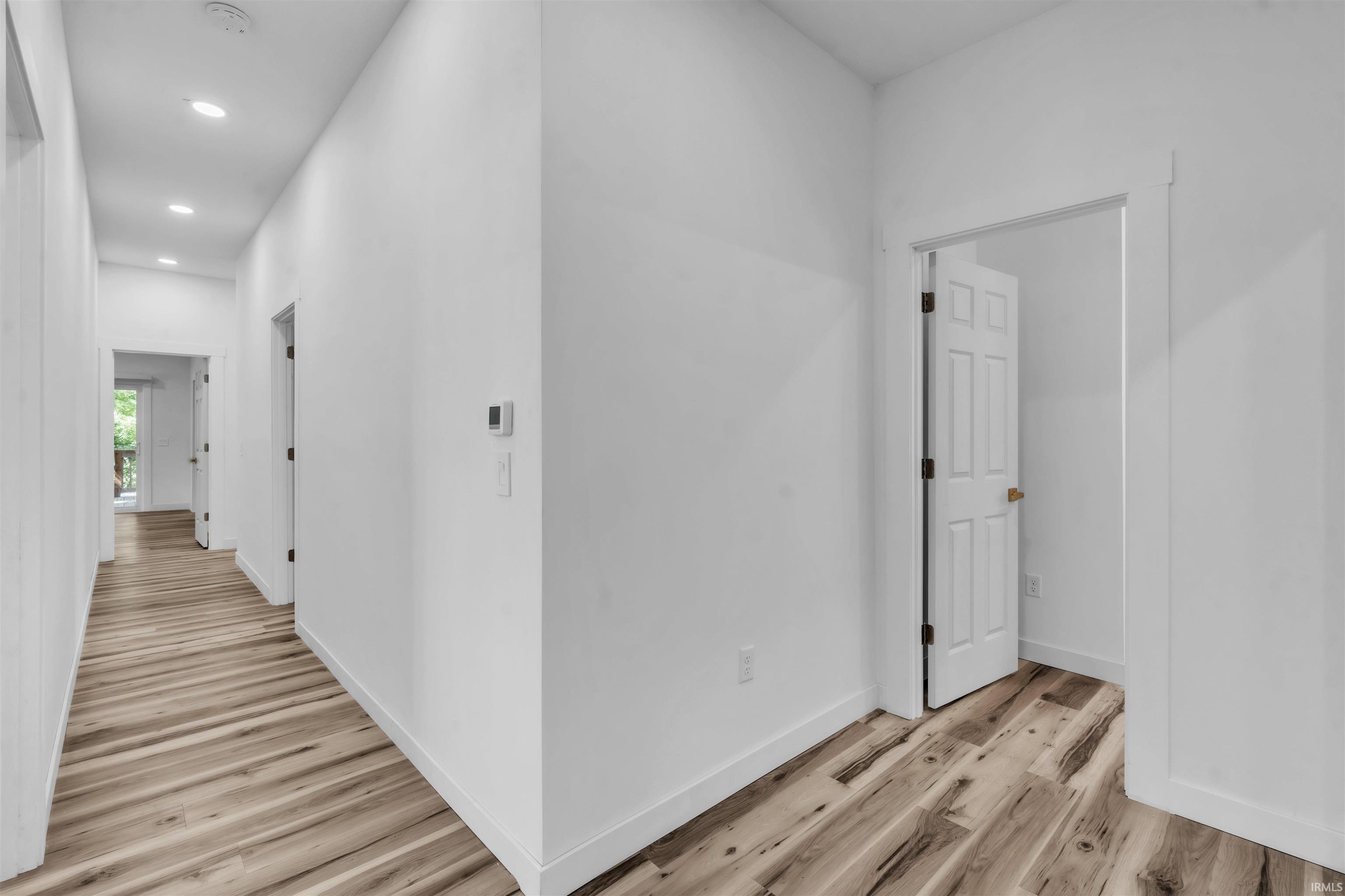 Hall with light wood finished floors and recessed lighting