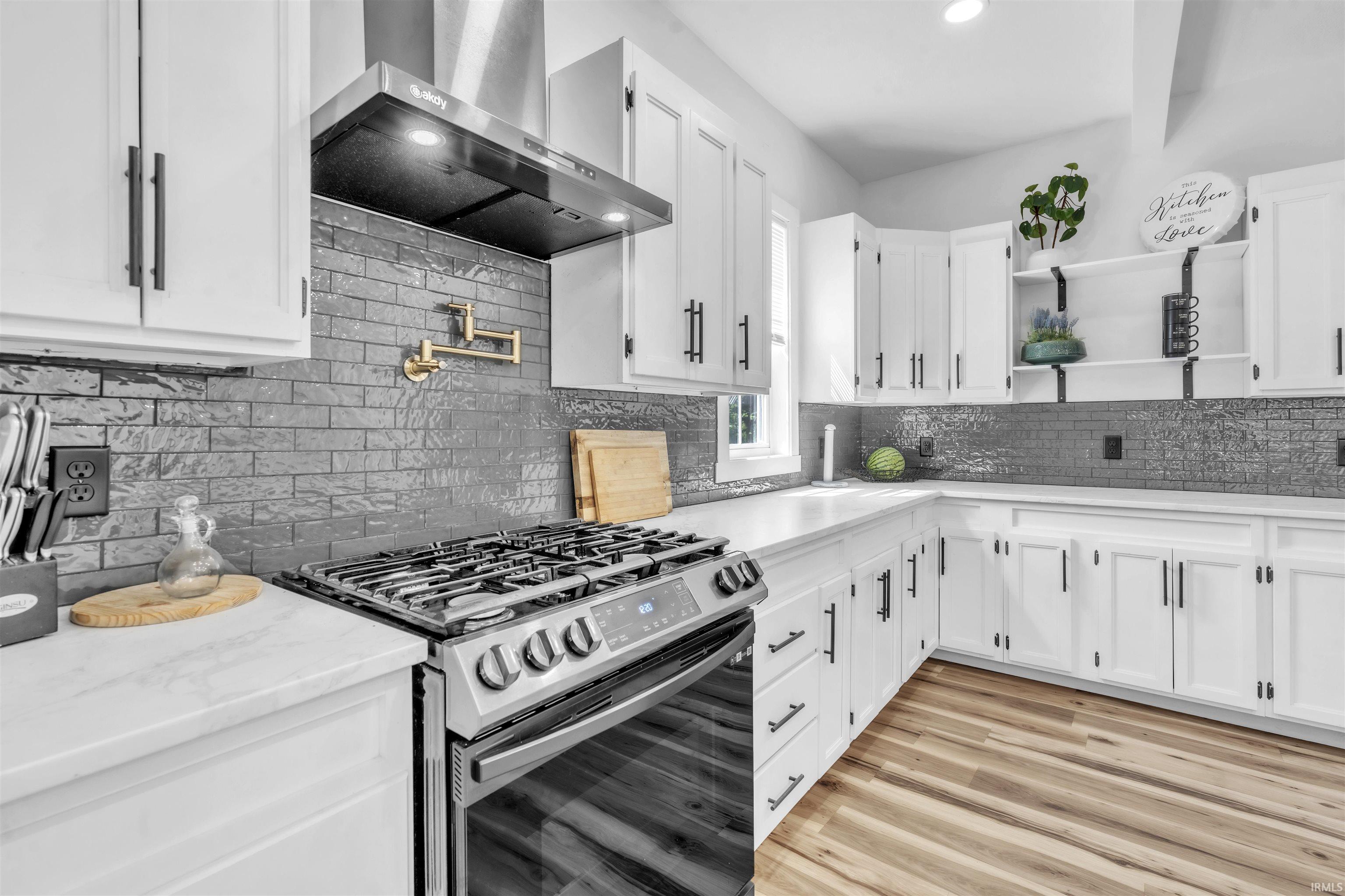 Kitchen with gas range oven, white cabinetry, recessed lighting, open shelves, and decorative backsplash
