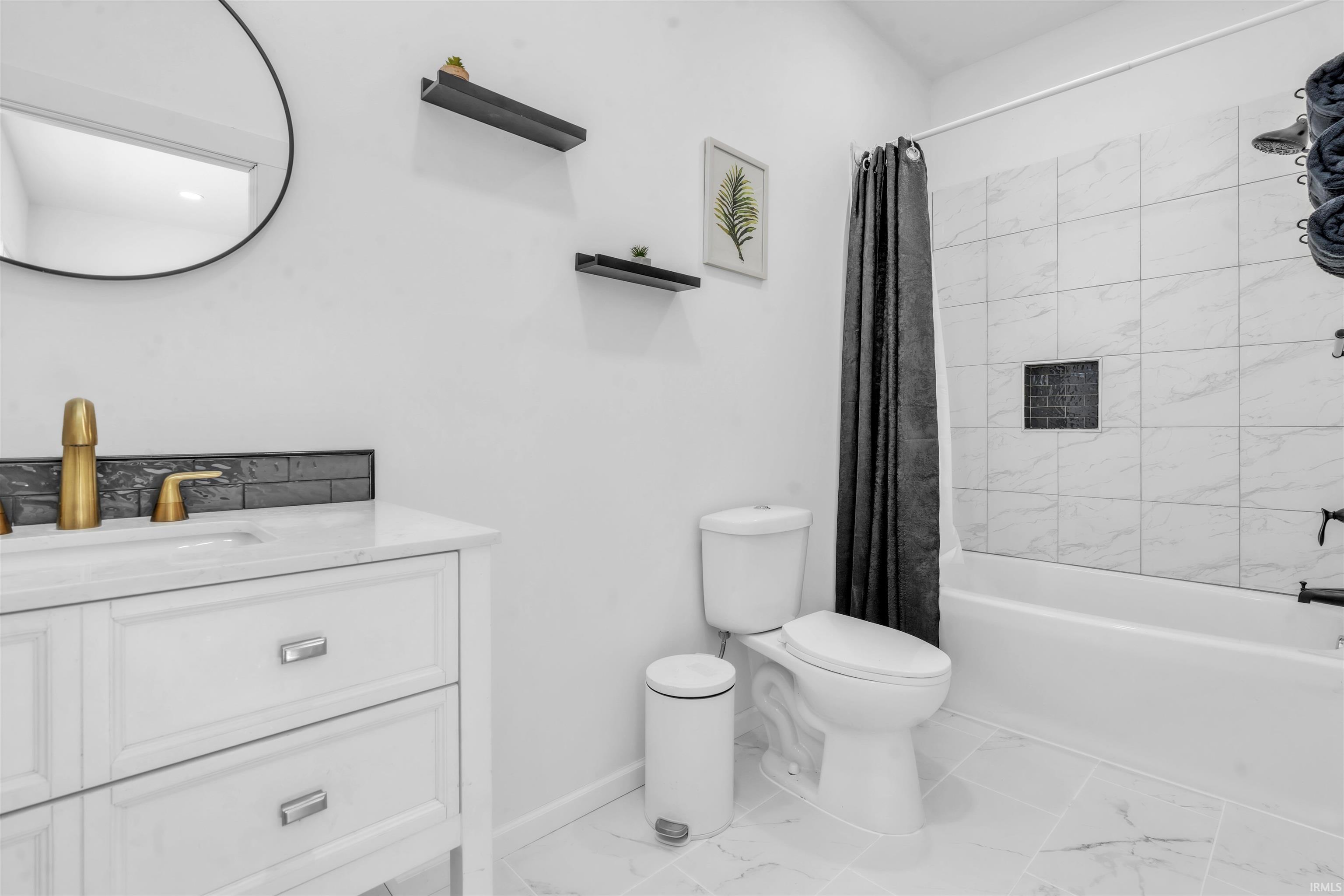 Bathroom with vanity, shower / bath combo with shower curtain, and light marble finish flooring