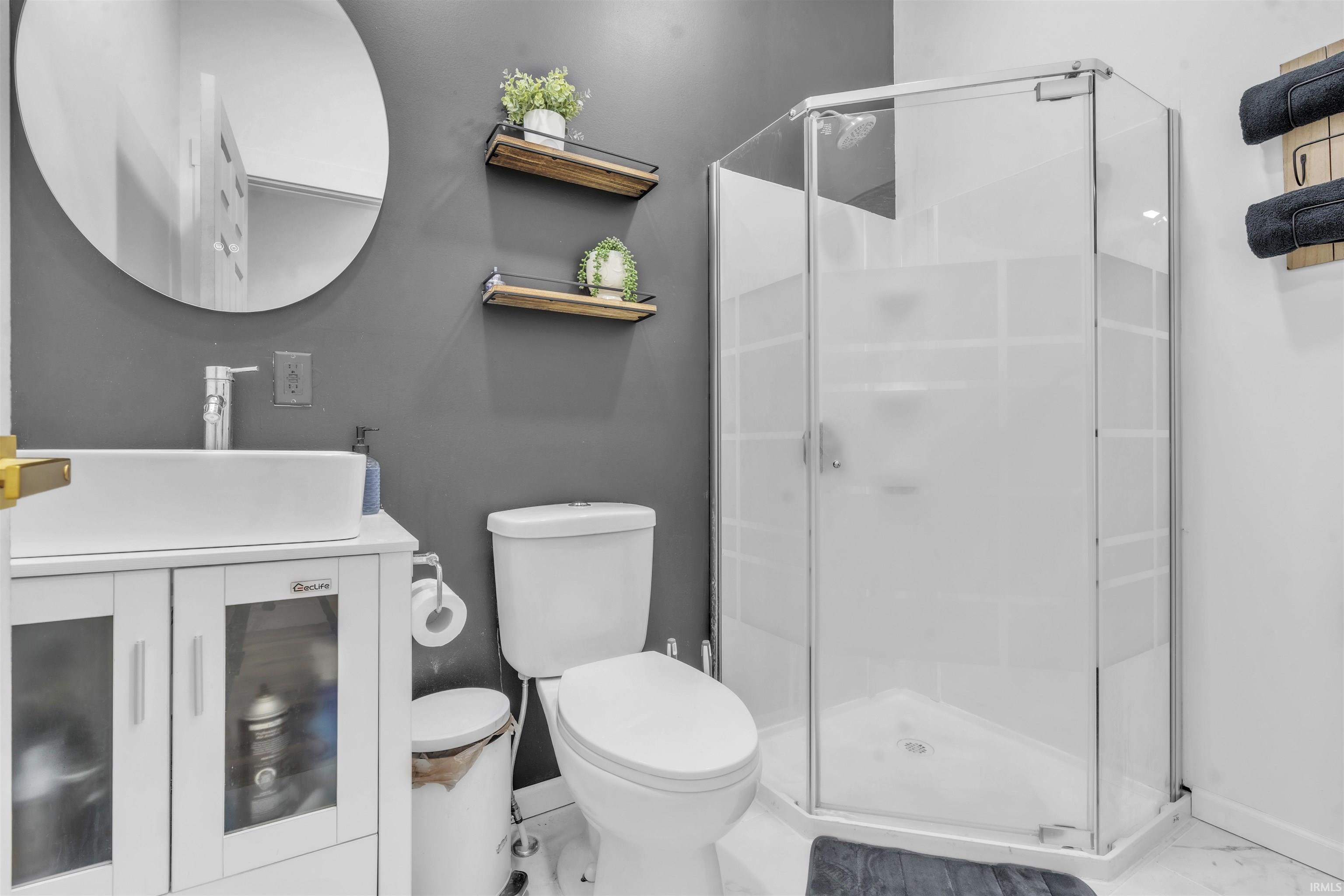 Bathroom with vanity, a stall shower, and marble look tiles