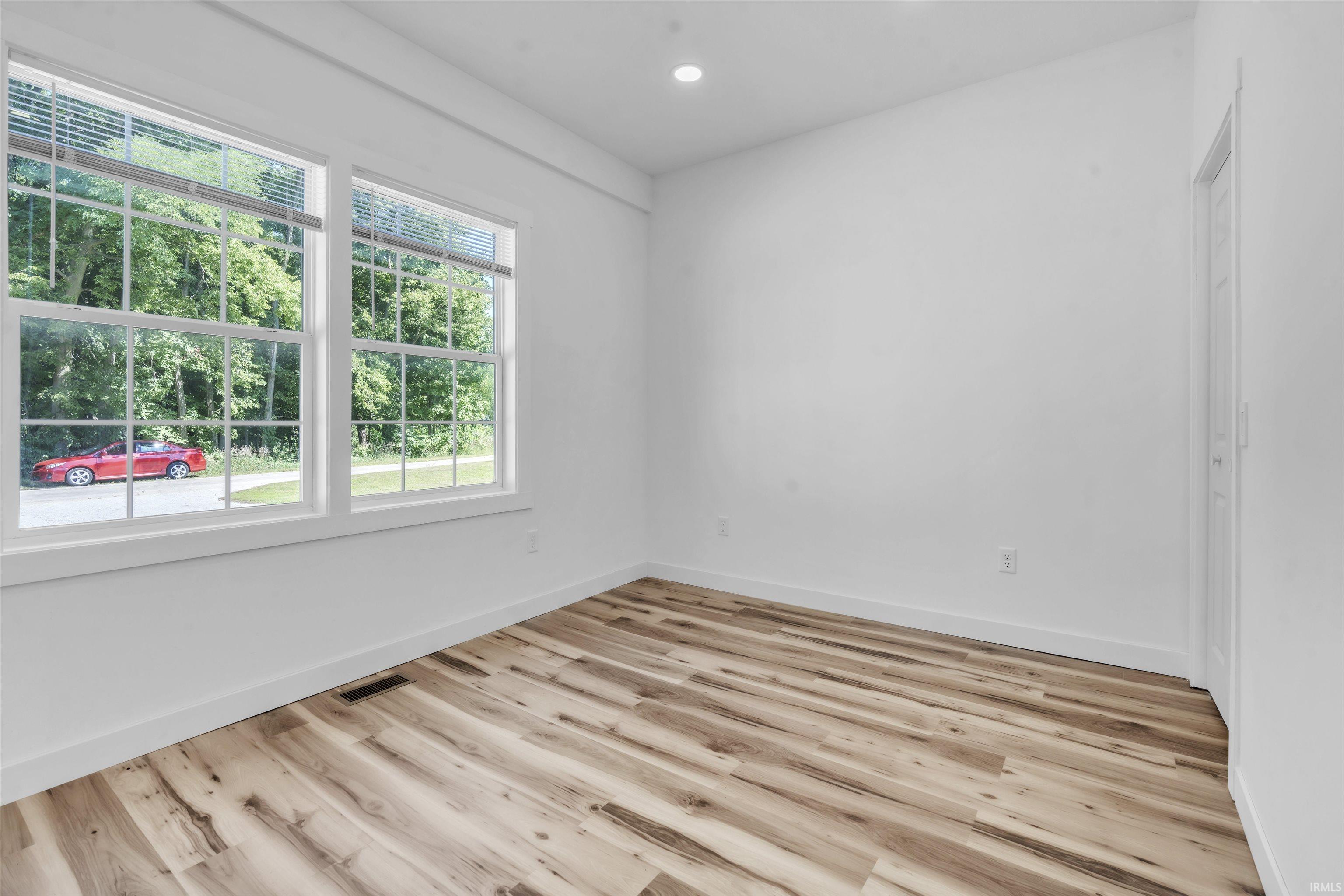 Empty room with light wood-style flooring and recessed lighting