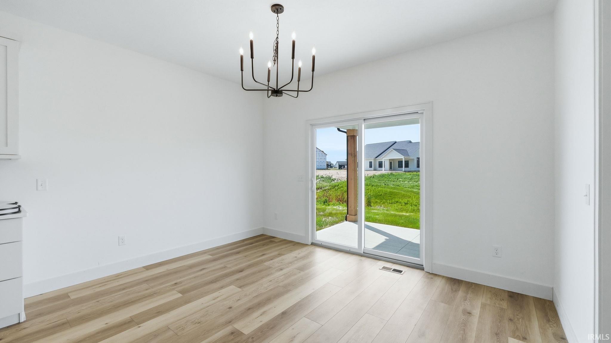 Dining area featuring a modern black chandelier, wood-finish flooring, and white baseboards