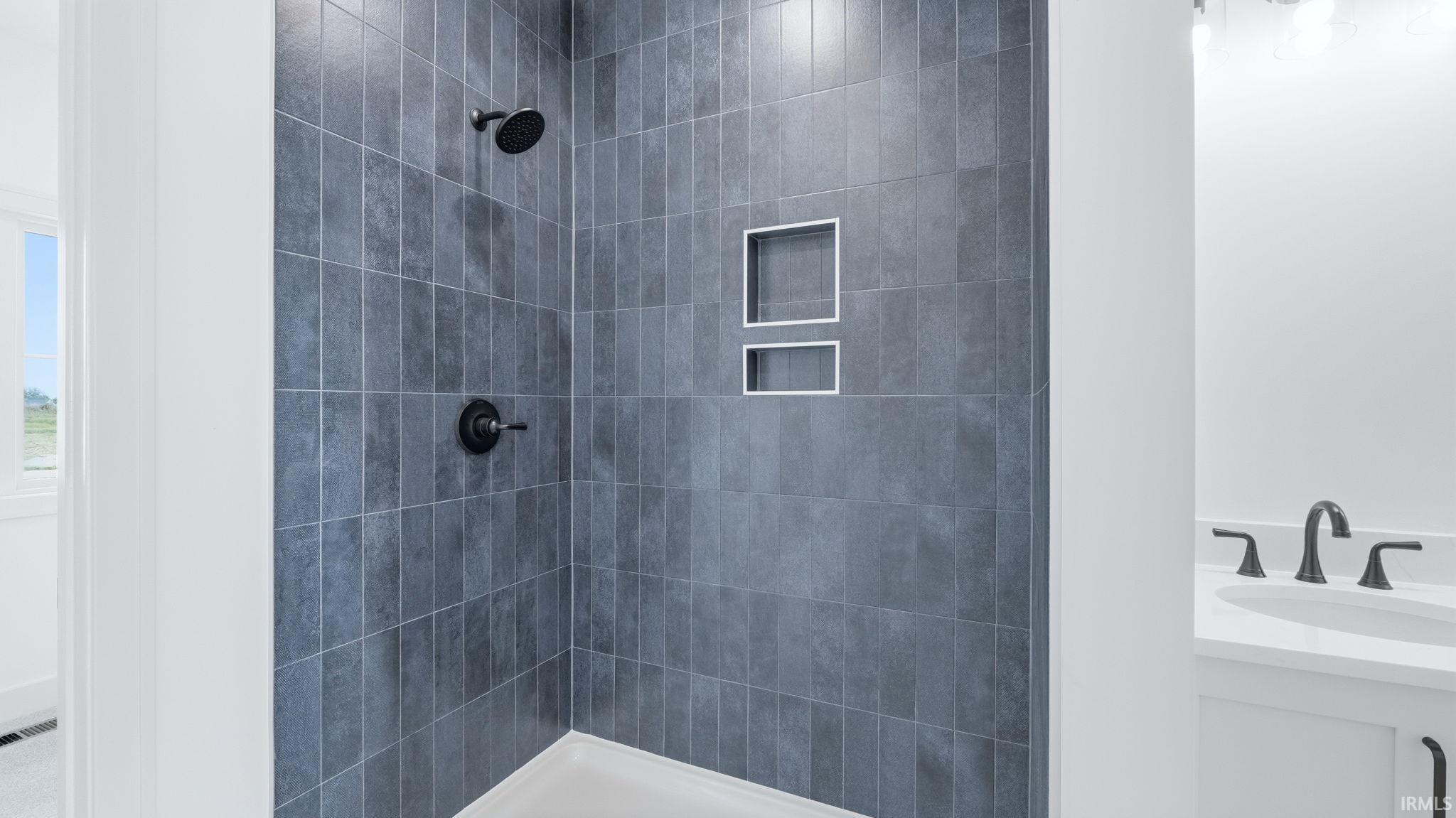 Walk-in shower with dark gray rectangular tile and two recessed niches
