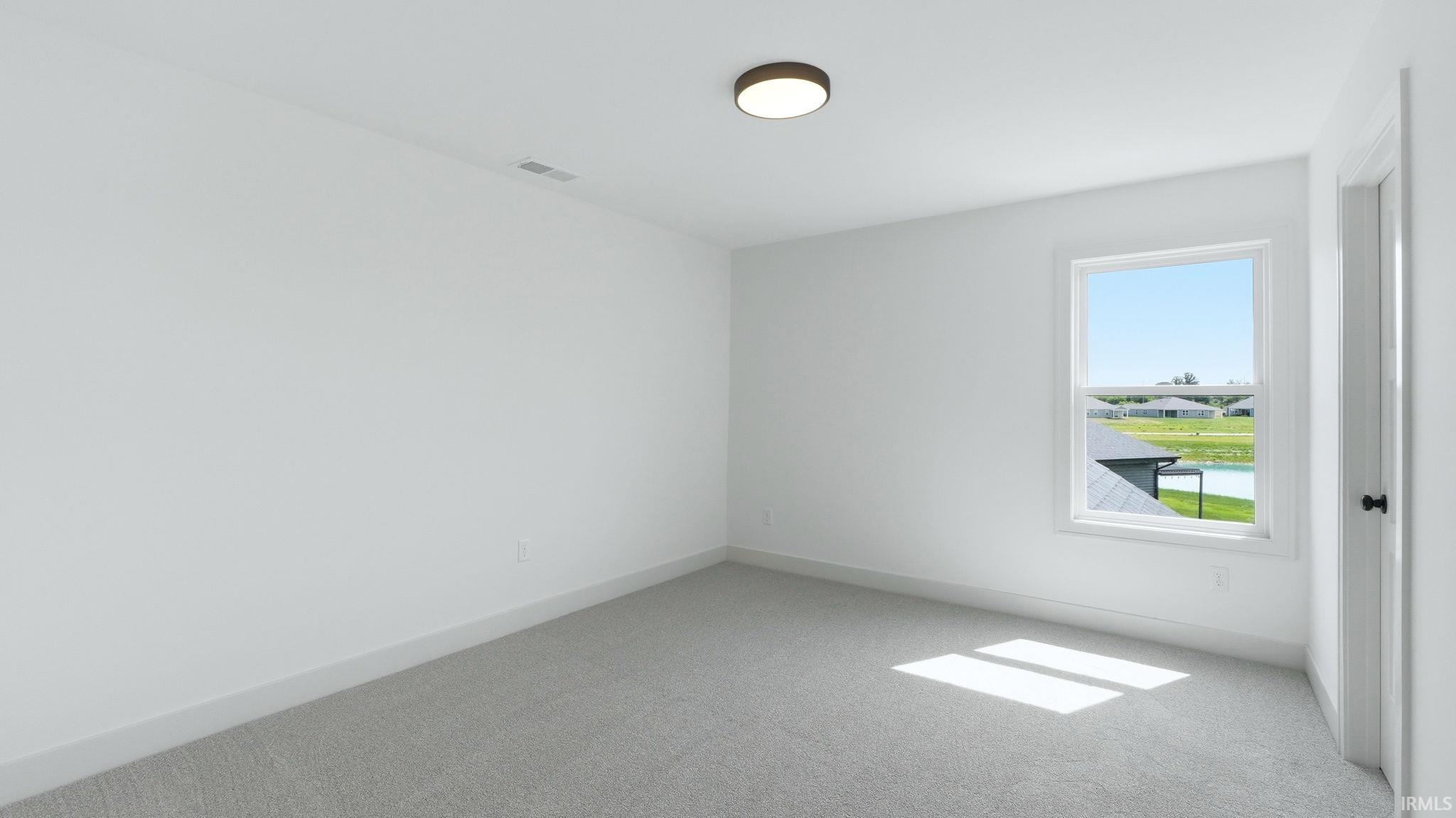 Carpeted room with a single window, white walls, and a ceiling-mounted light fixture