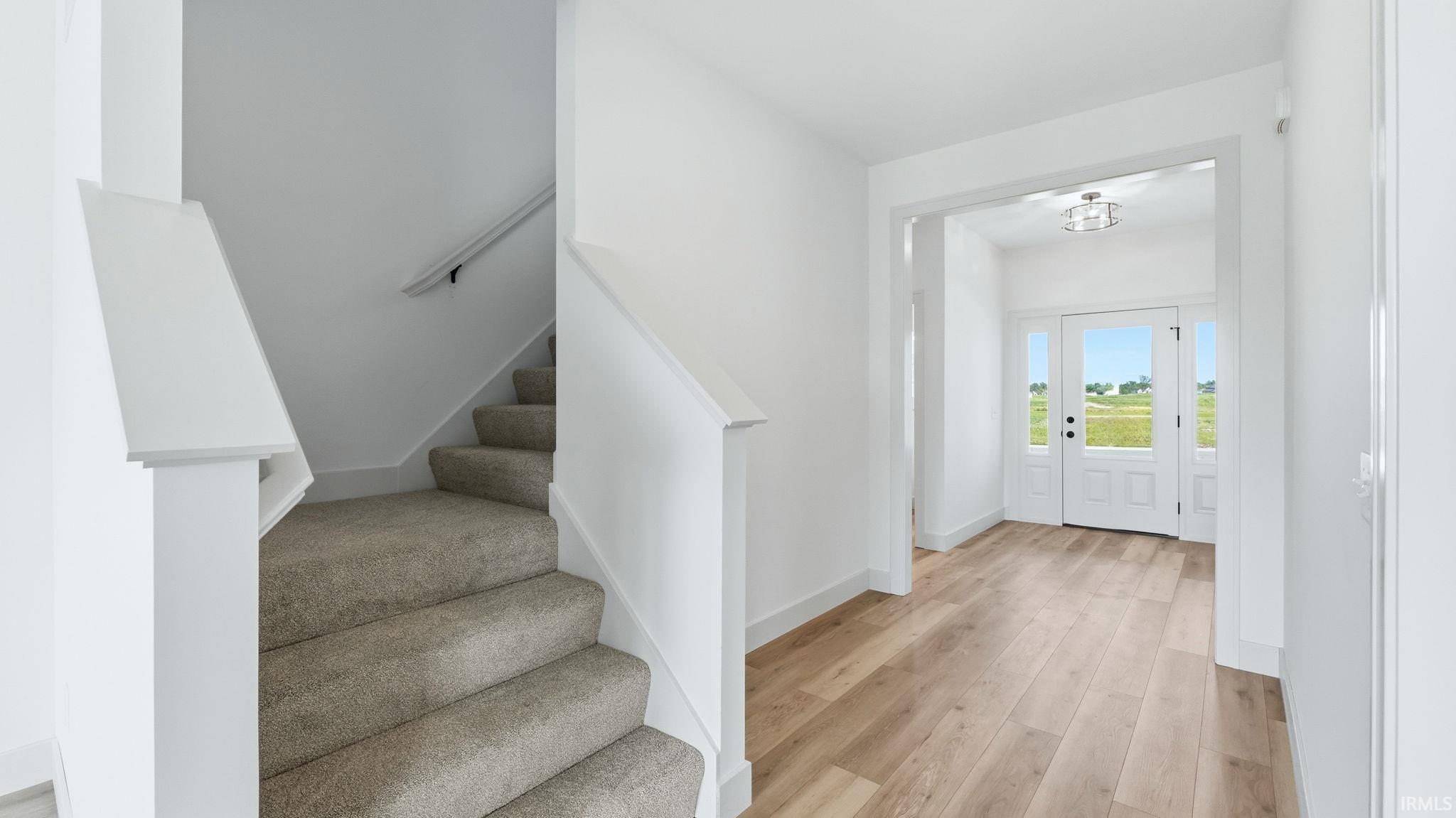 Foyer featuring light wood-finish flooring, white walls, and a white front door with sidelight windows