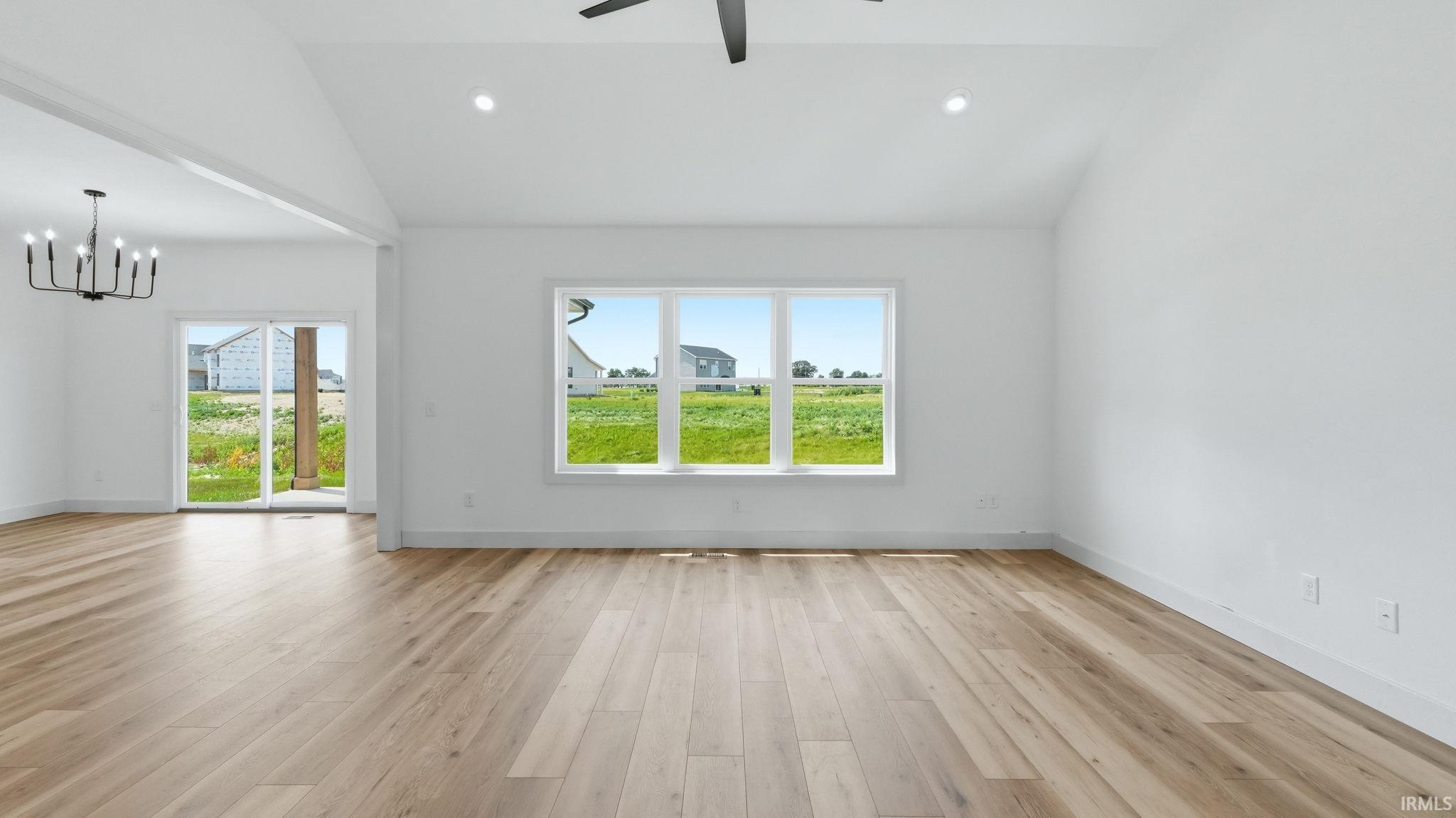Vaulted ceilings with recessed lighting, wood-finish flooring, a contemporary black ceiling fan, and a three-panel window