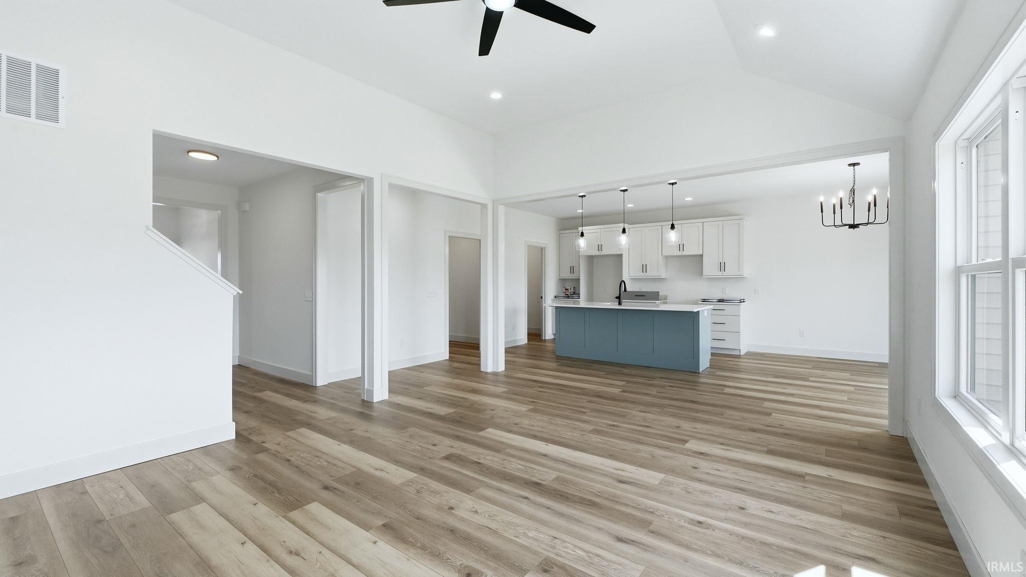 Spacious open-concept interior featuring wood-finish flooring and a vaulted ceiling